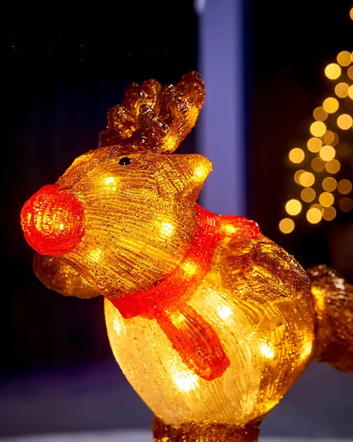 Close-up of pre-lit acrylic reindeer figurine showing the red nose, antlers and glowing LED lights