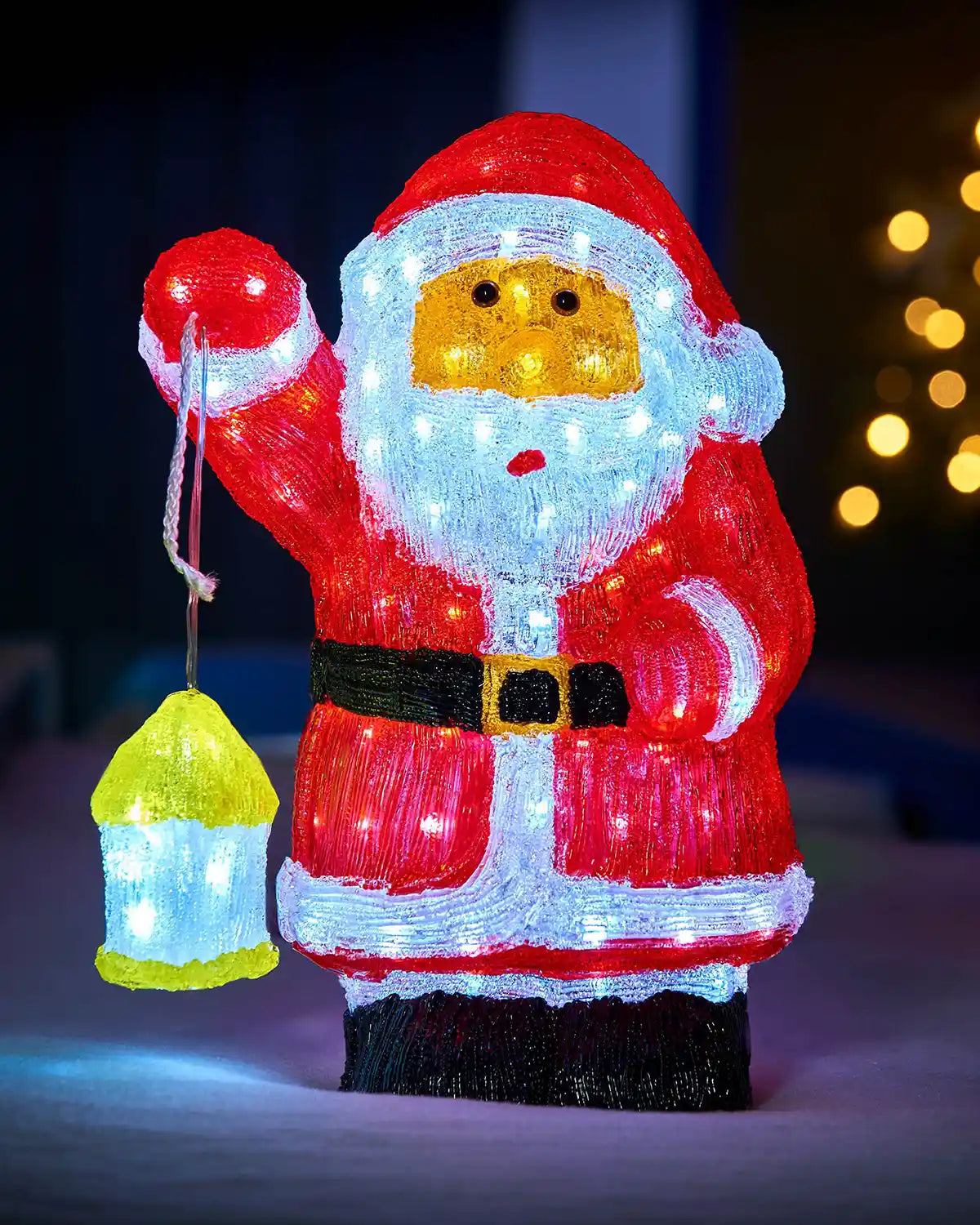 Front view of illuminated acrylic Santa figurine holding a lantern in an outdoor Christmas display