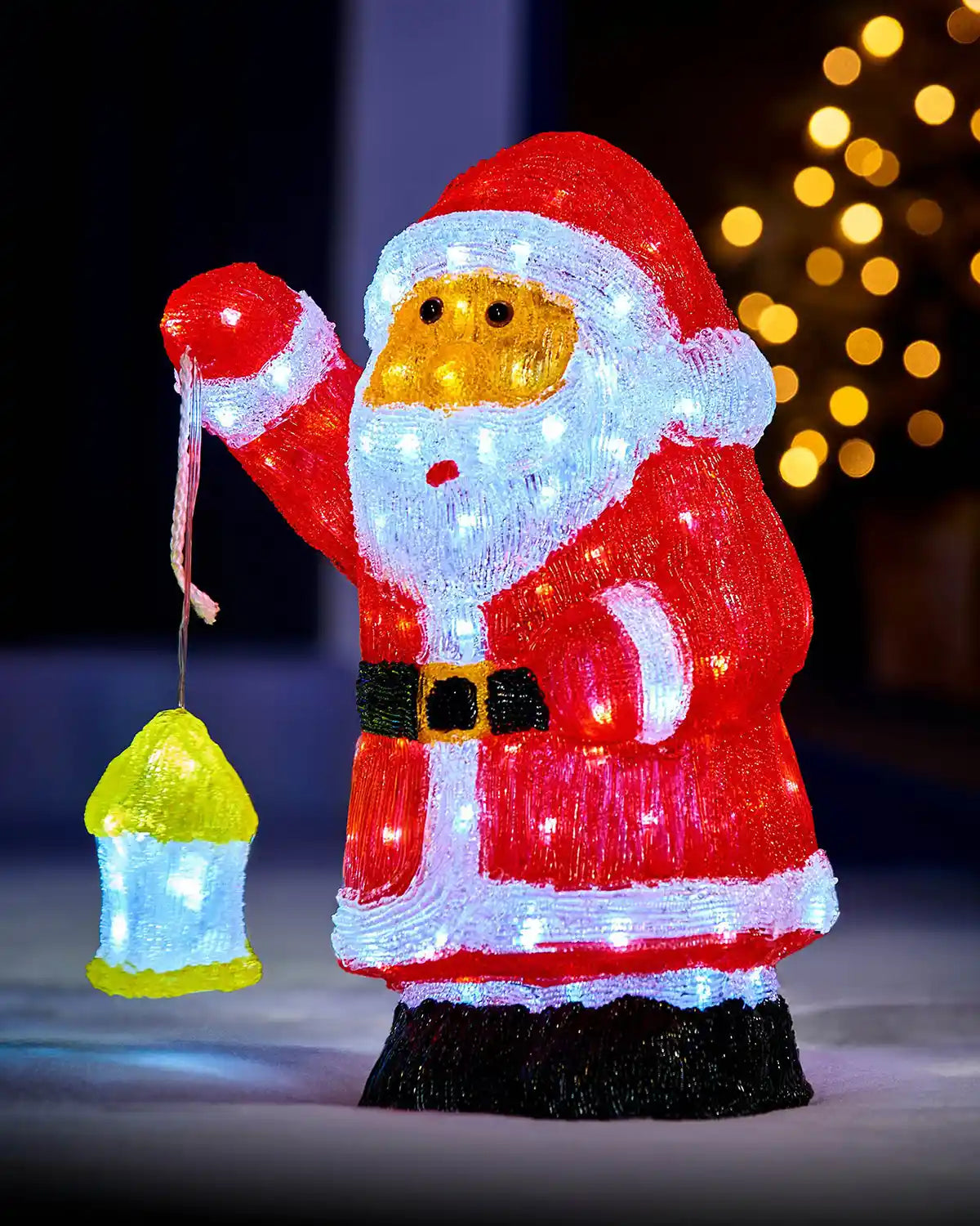 Pre-lit acrylic Santa figurine glowing outdoors with a lantern and festive lights in the background
