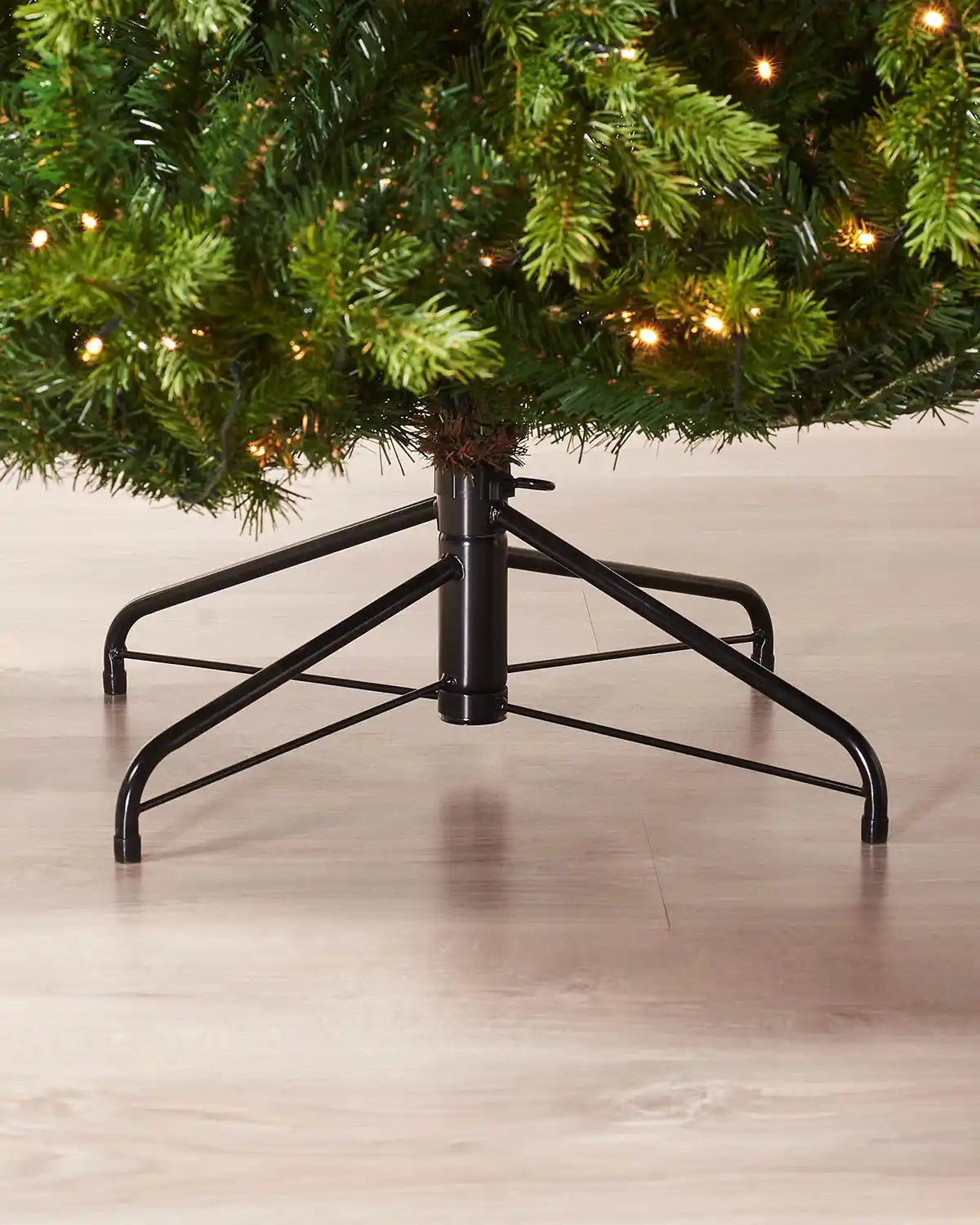 Close-up of the black metal stand and lower branches of a 7 ft pre-lit Balsam Fir Christmas tree
