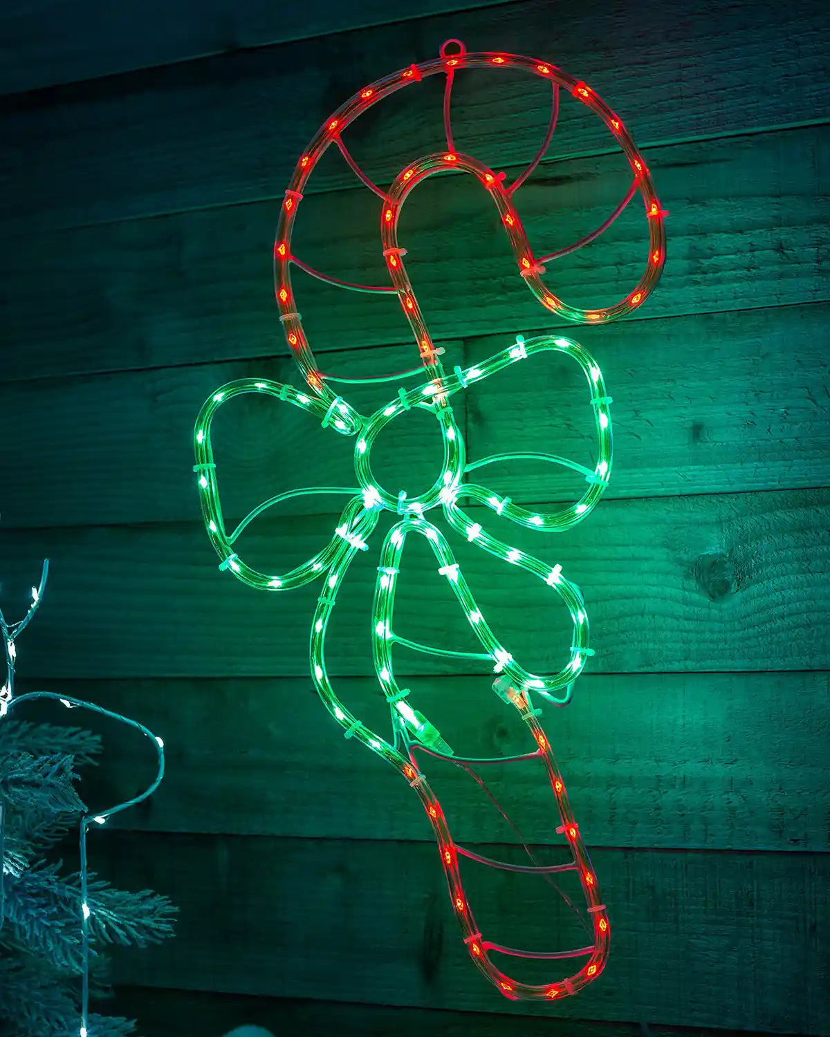 Pre-lit candy cane rope light displayed on a wooden wall at night