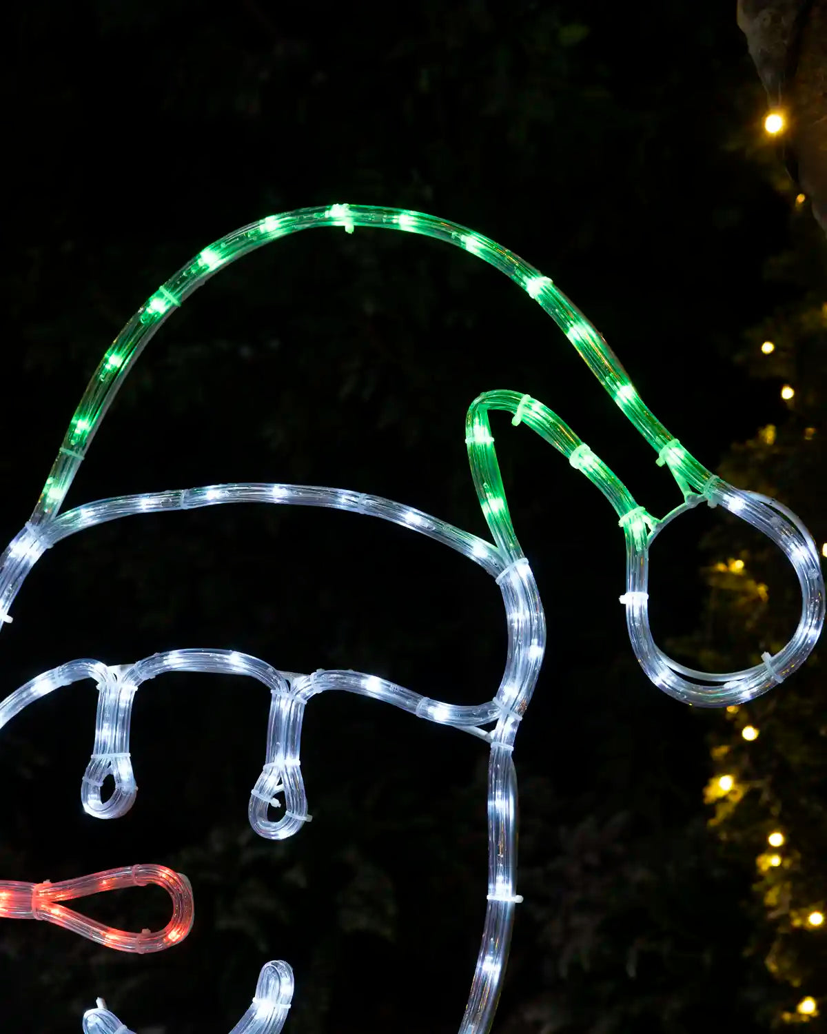 Close-up of a snowman wearing an illuminated green and white Santa hat.