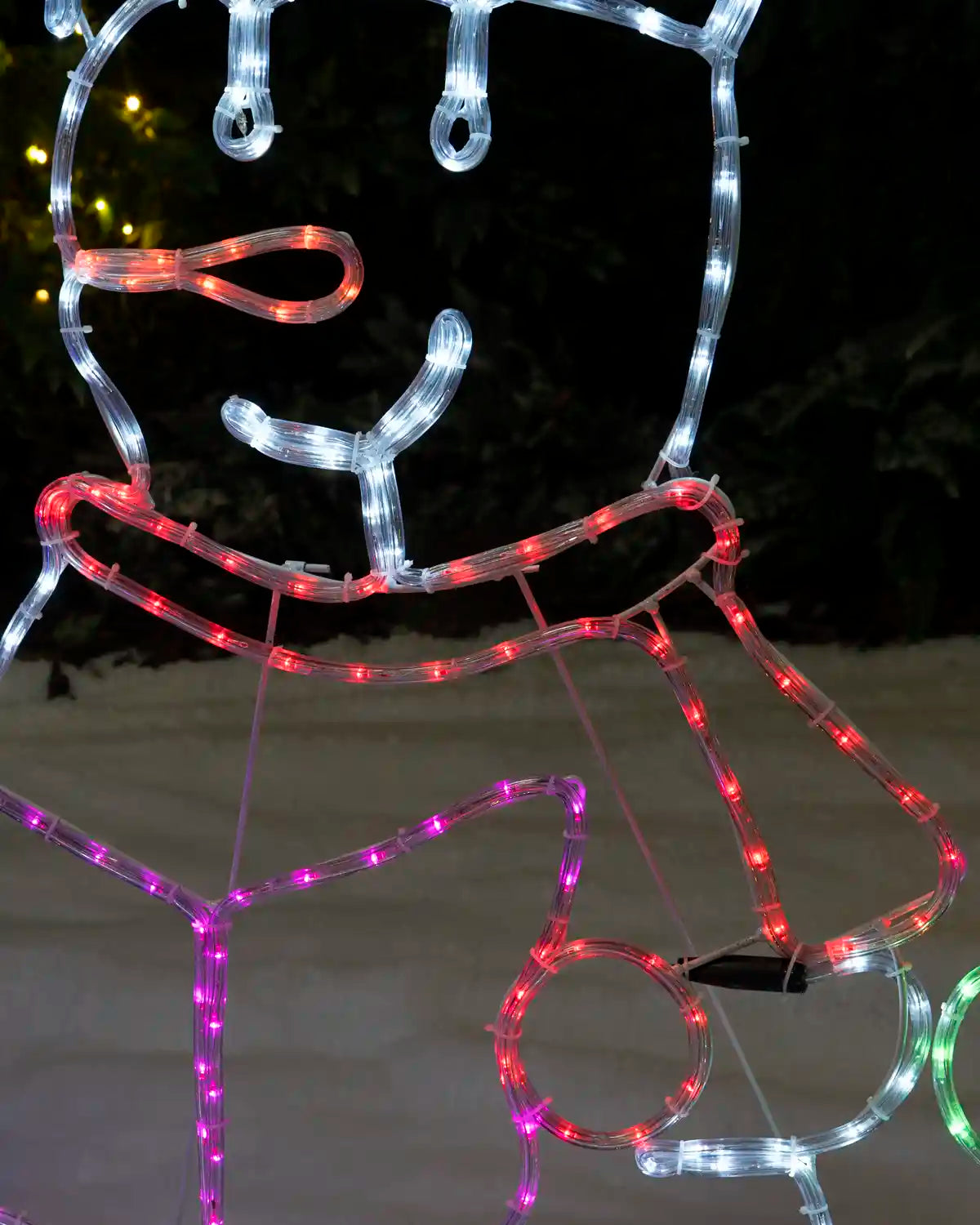 Close-up of a carolling snowman with red illuminated scarf and multicolour songbook.