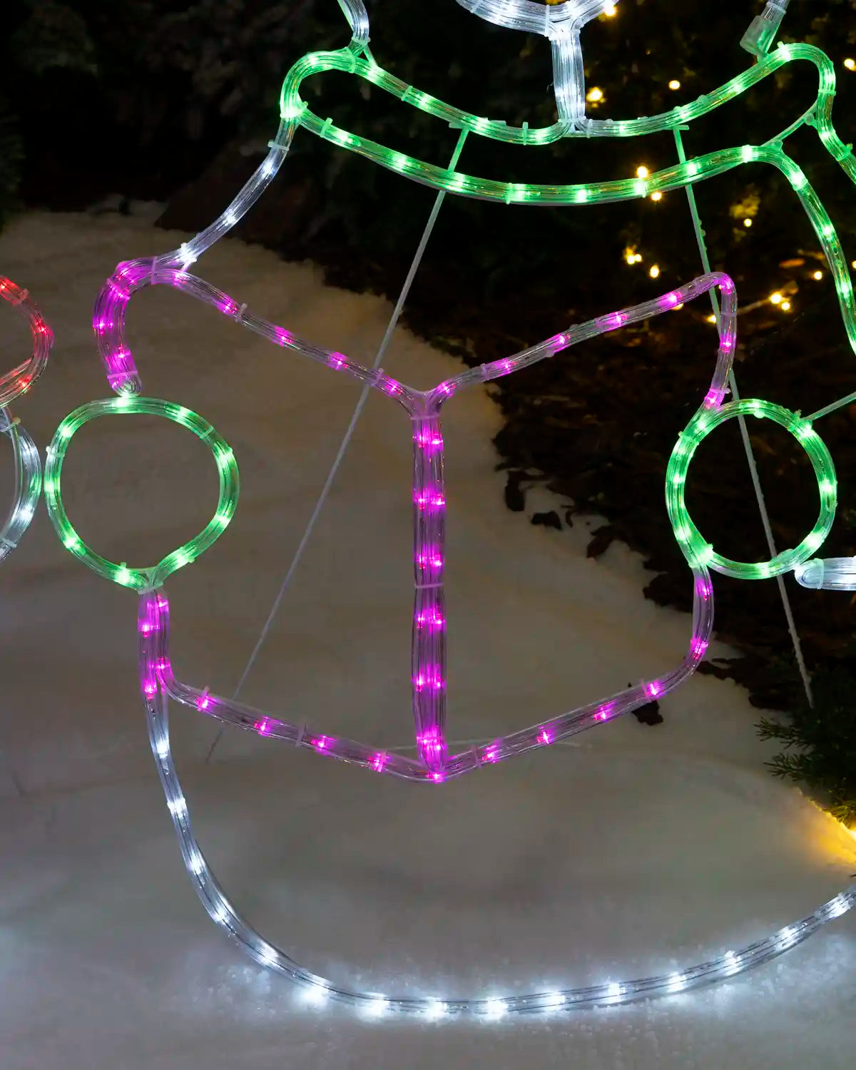 Close-up of the illuminated songbook and lower body with green, purple and white rope lights.
