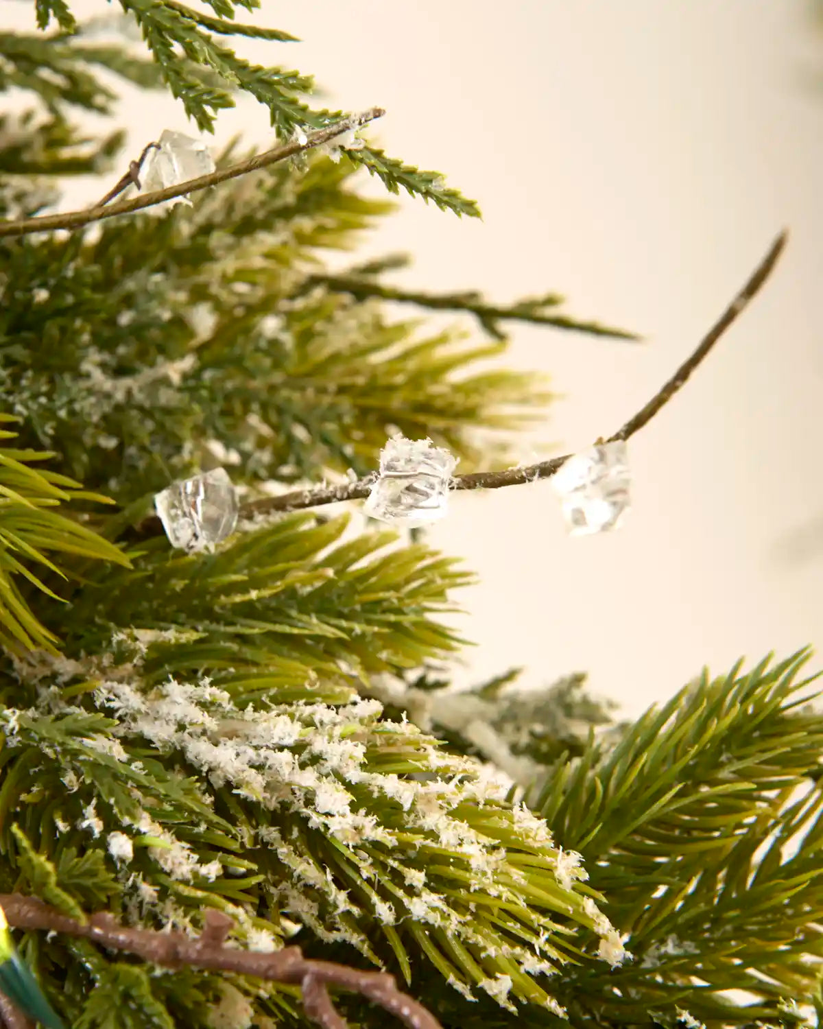 Close-up of clear crystal-style decorations and snow flocked foliage on the pre-lit garland.