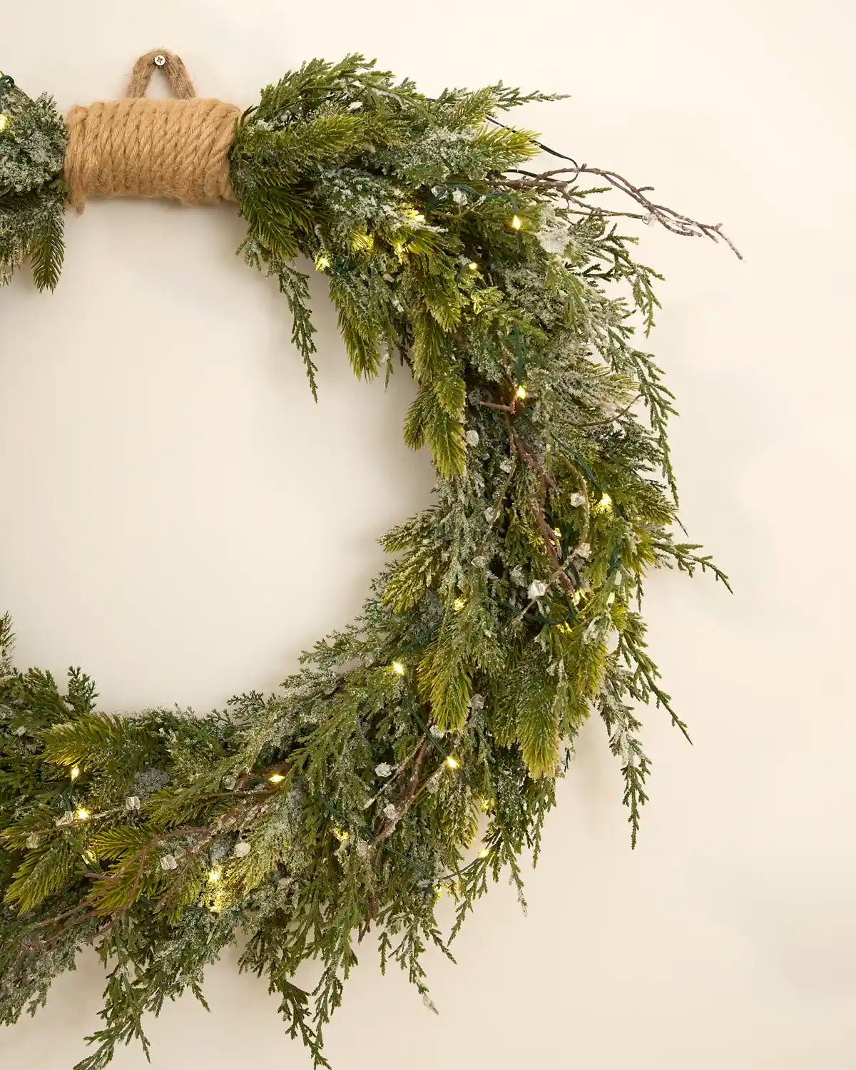 Close-up of the snow flocked mixed foliage and warm white lights on the wreath.