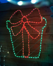 Pre-lit giftbox rope light displayed on a wooden wall at night