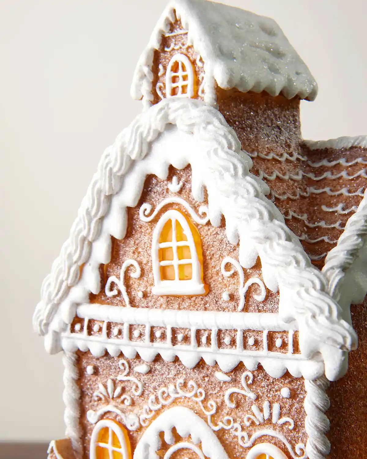 Close-up of the pre-lit gingerbread house roof and upper window with white icing-style trim and glitter finish.