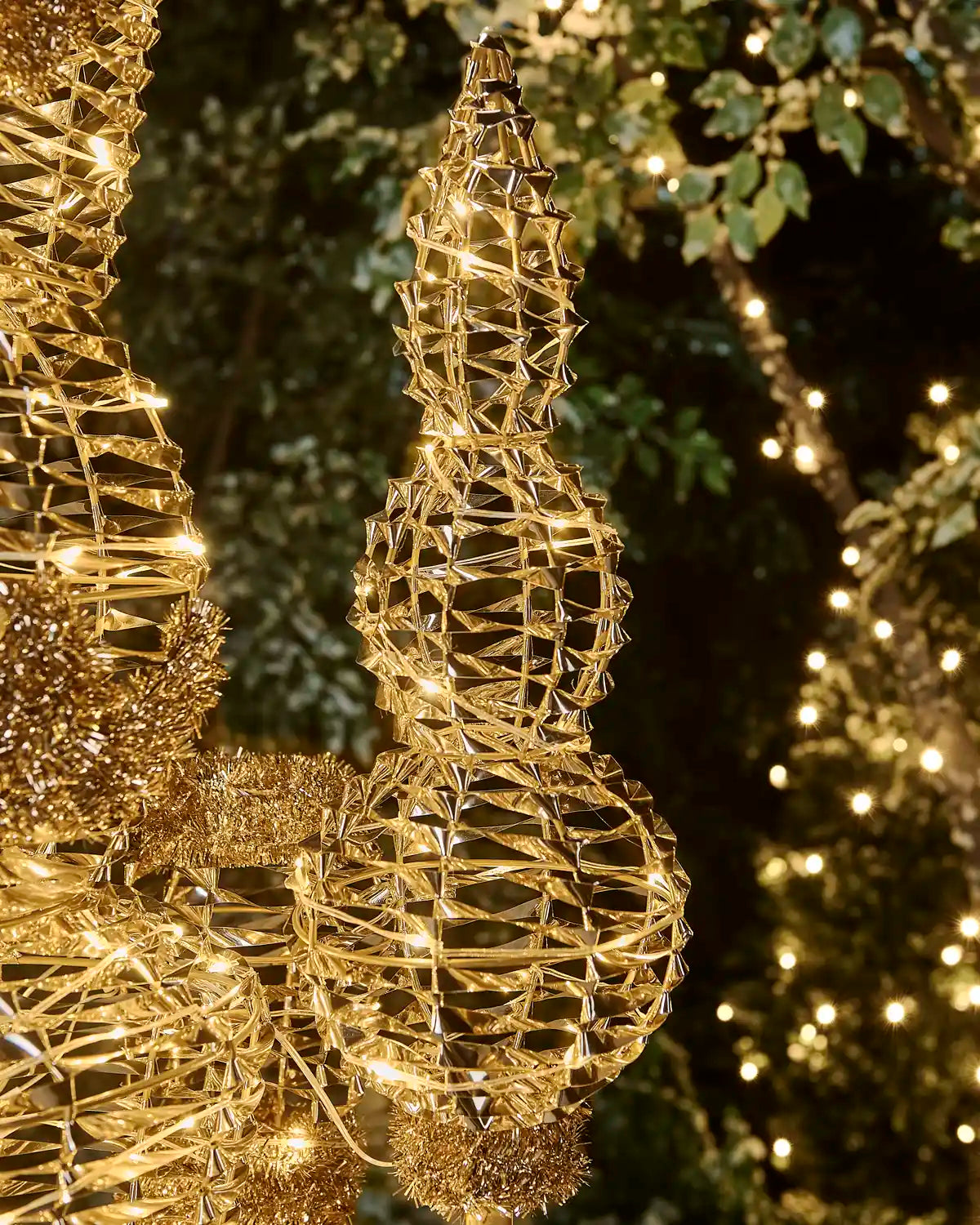 Close-up of the gold nutcracker’s illuminated decorative staff with woven metallic detailing and tinsel trim.