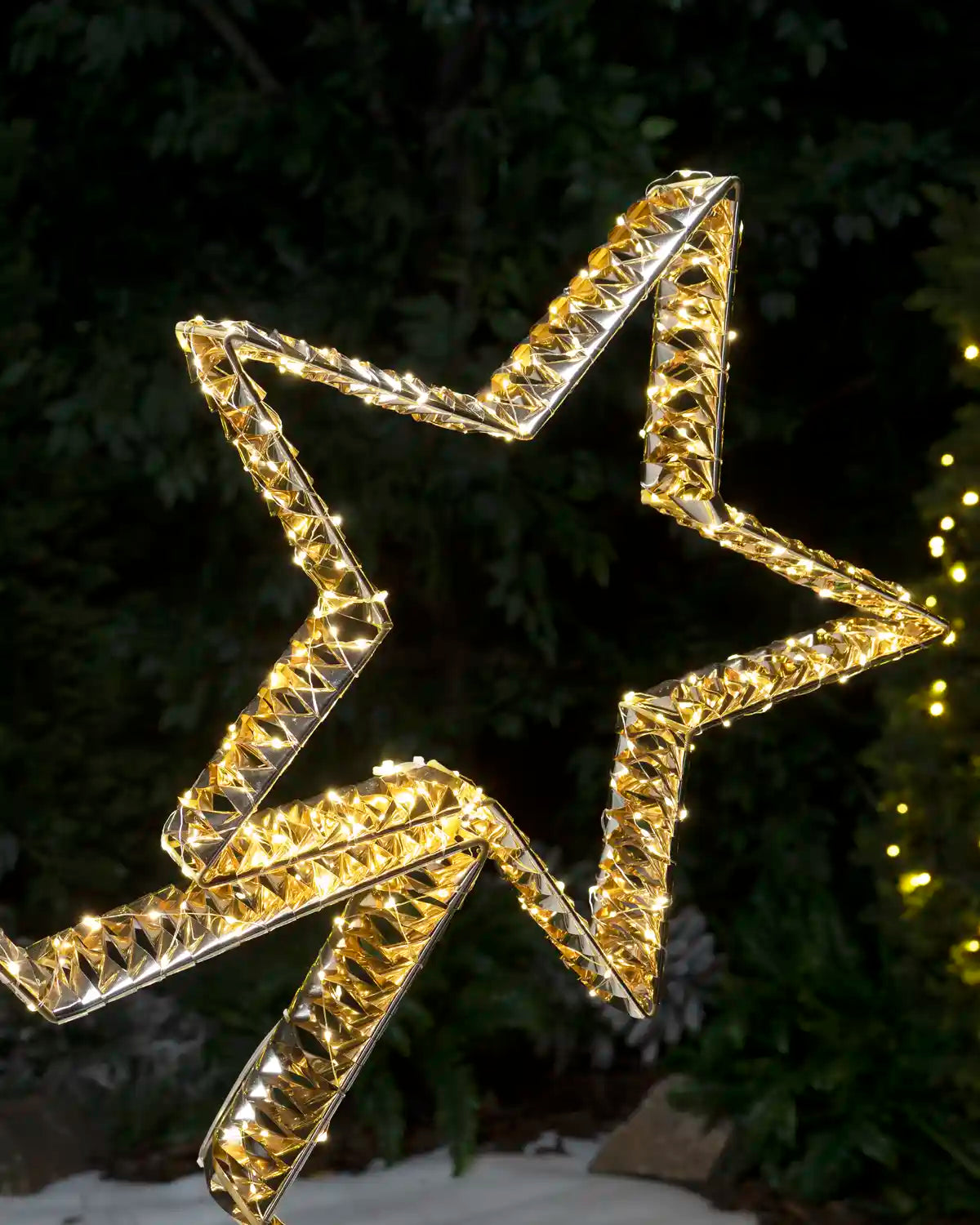 Close-up of the upper illuminated gold star showing its angular outline and warm white LEDs.