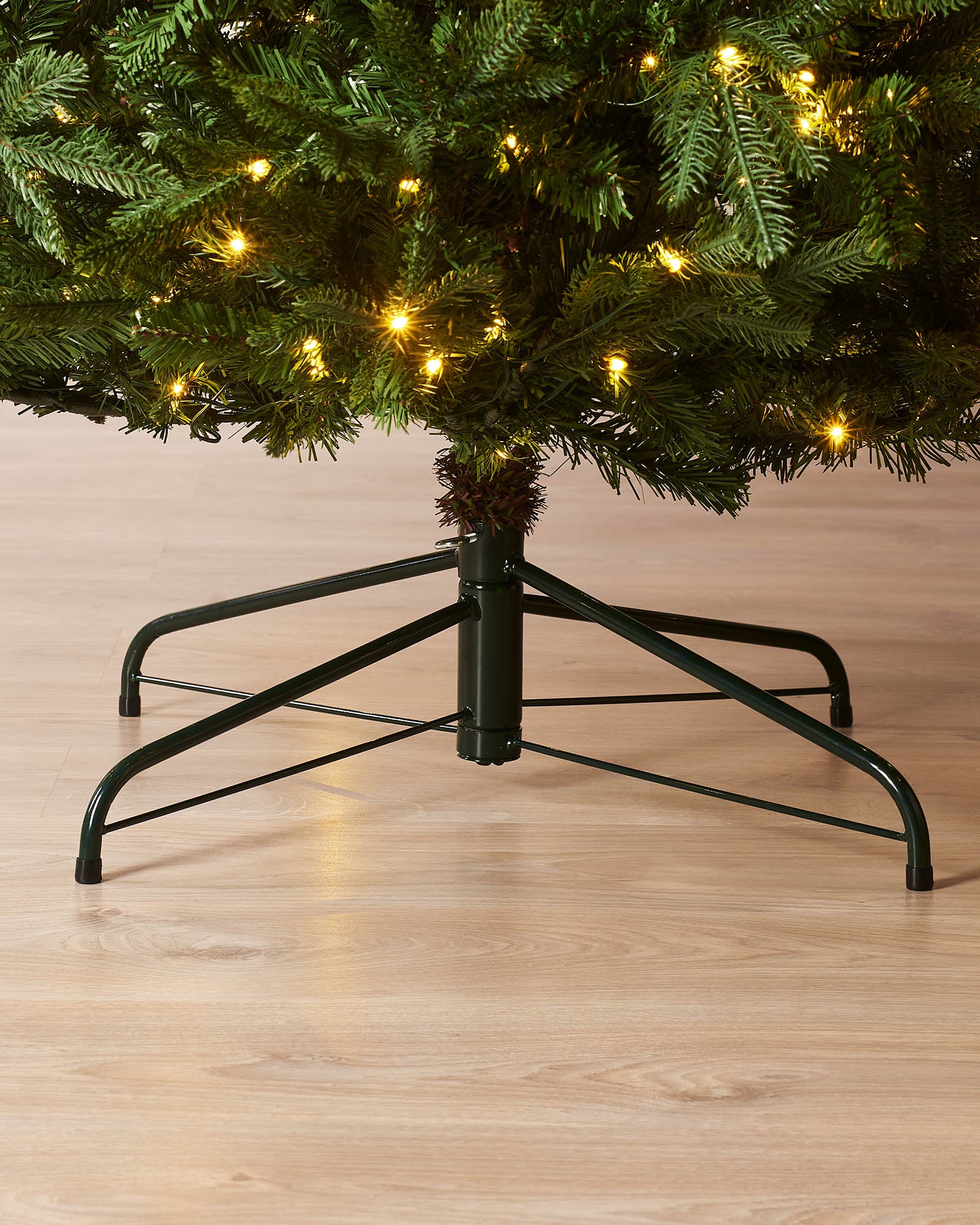 Close-up of the black metal tree stand beneath a pre-lit Grand Nordmann fir Christmas tree.