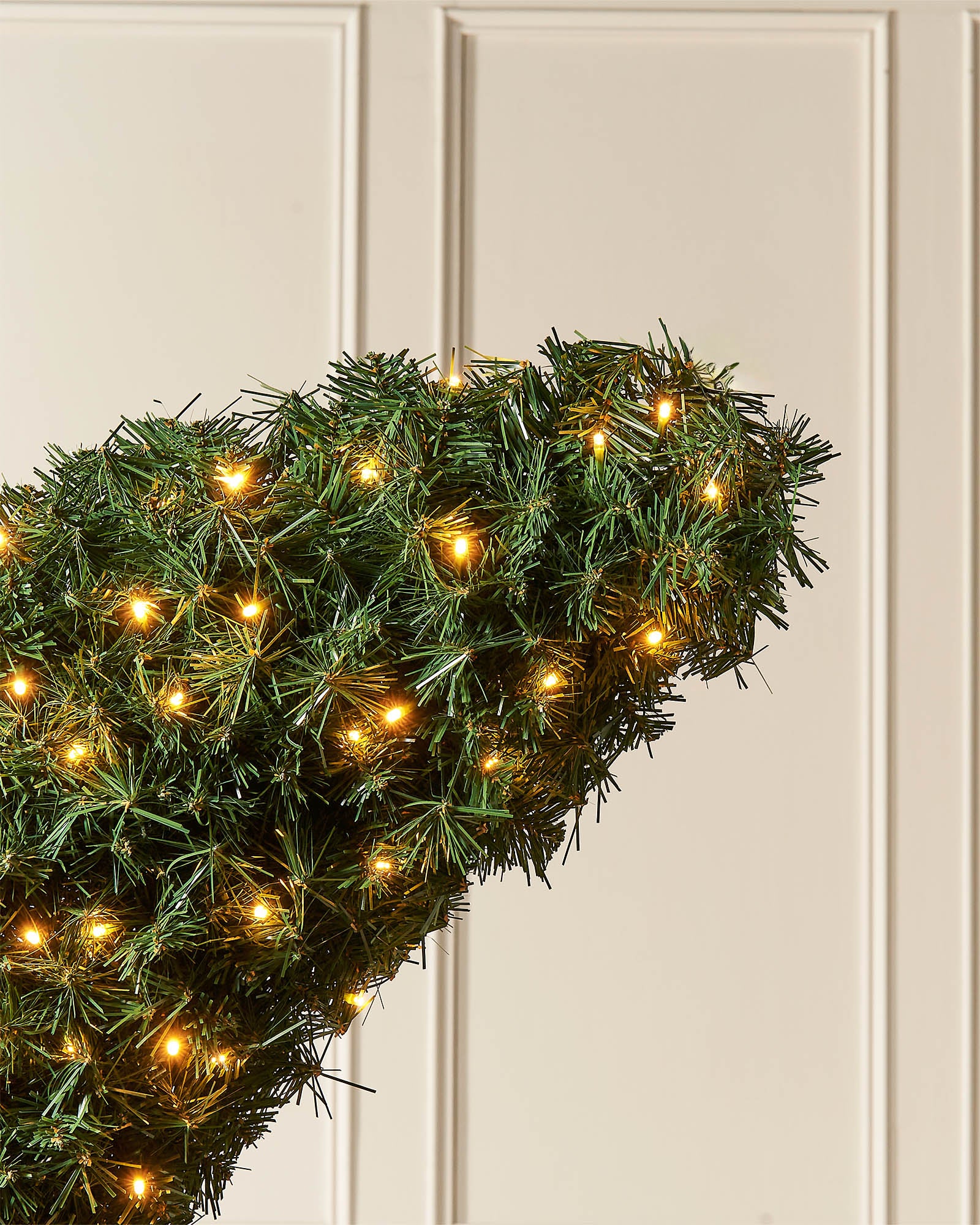 Top close-up of the pre-lit half moon Christmas tree showing dense green foliage and warm white lights.