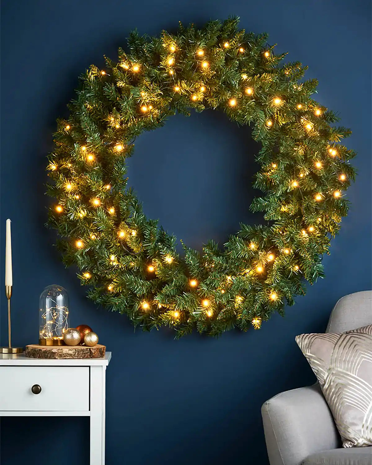 1 m pre-lit majestic Christmas wreath displayed on a blue wall with warm white lights