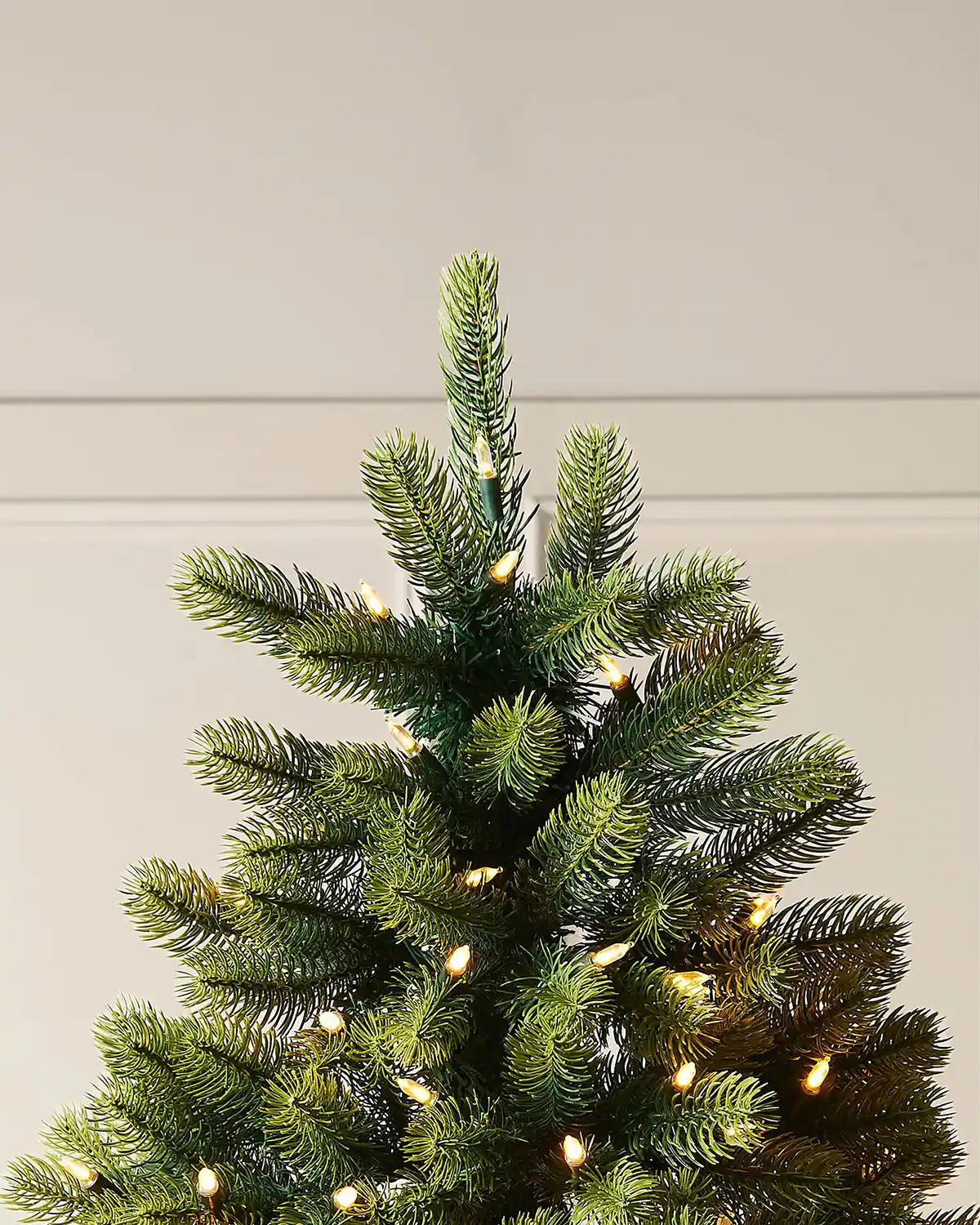Close-up of the shaped top section of a pre-lit mixed pine half Christmas tree.