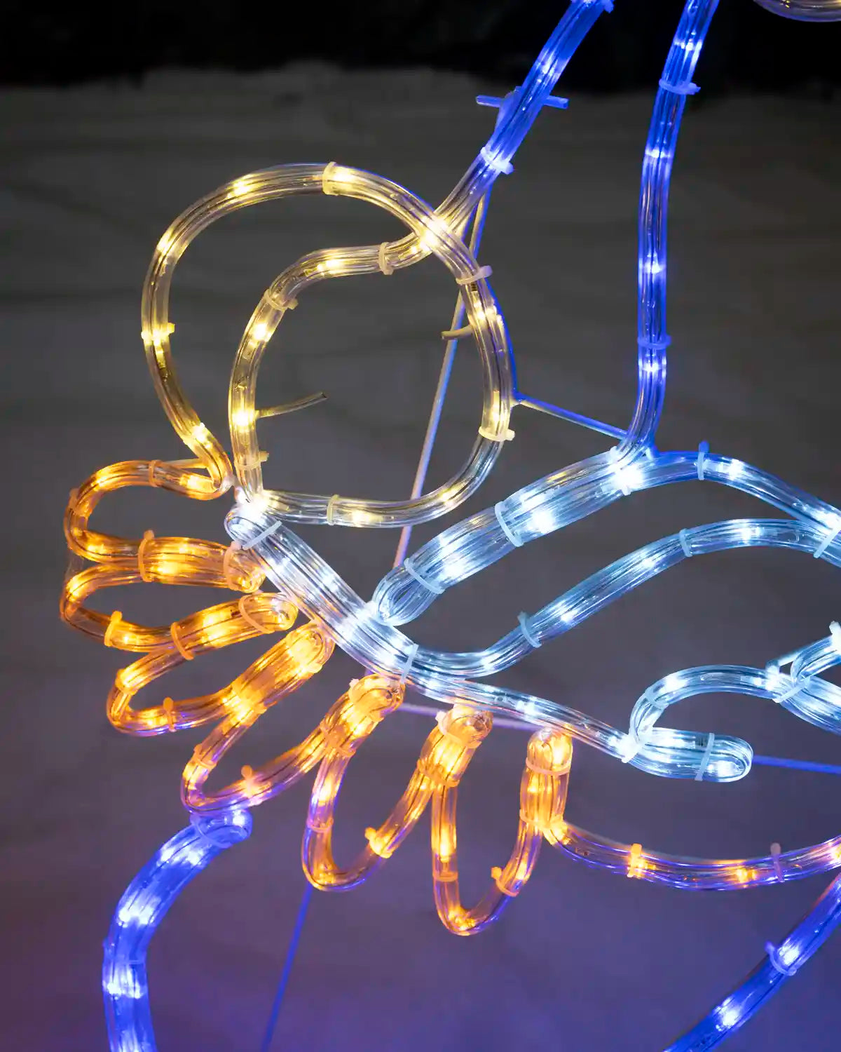Close-up of Mary holding baby Jesus with blue, white and warm white rope lights.