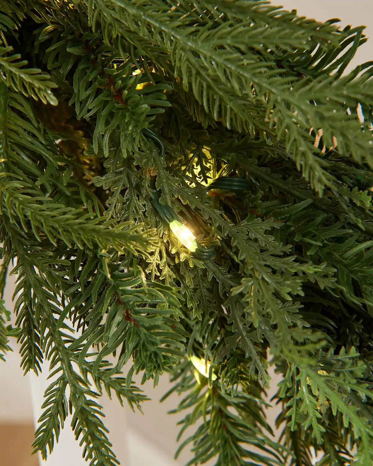 Detail close-up of the pre-lit fir garland showing layered foliage and warm white lights.