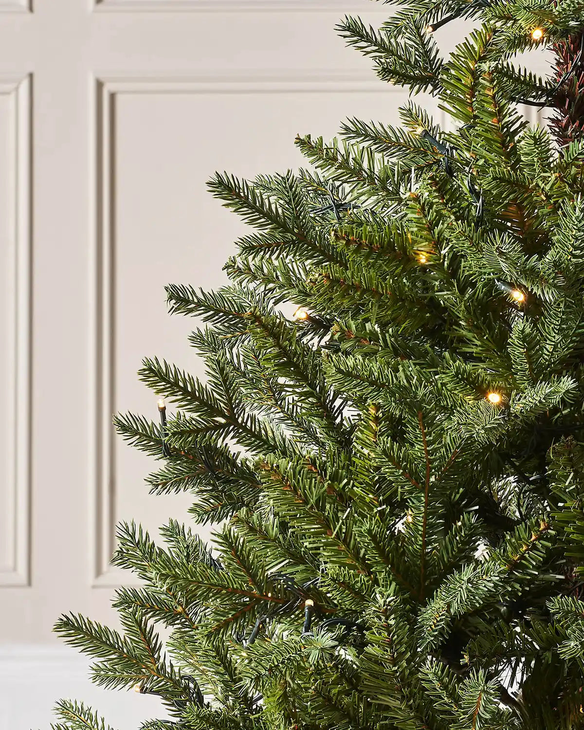 Close-up of green artificial spruce branches with warm lights