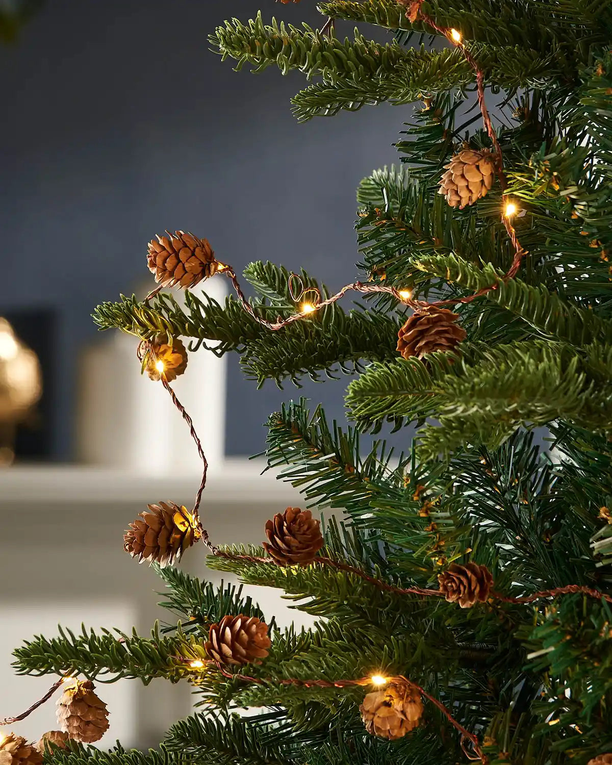Pre-lit pinecone light string styled around a Christmas tree