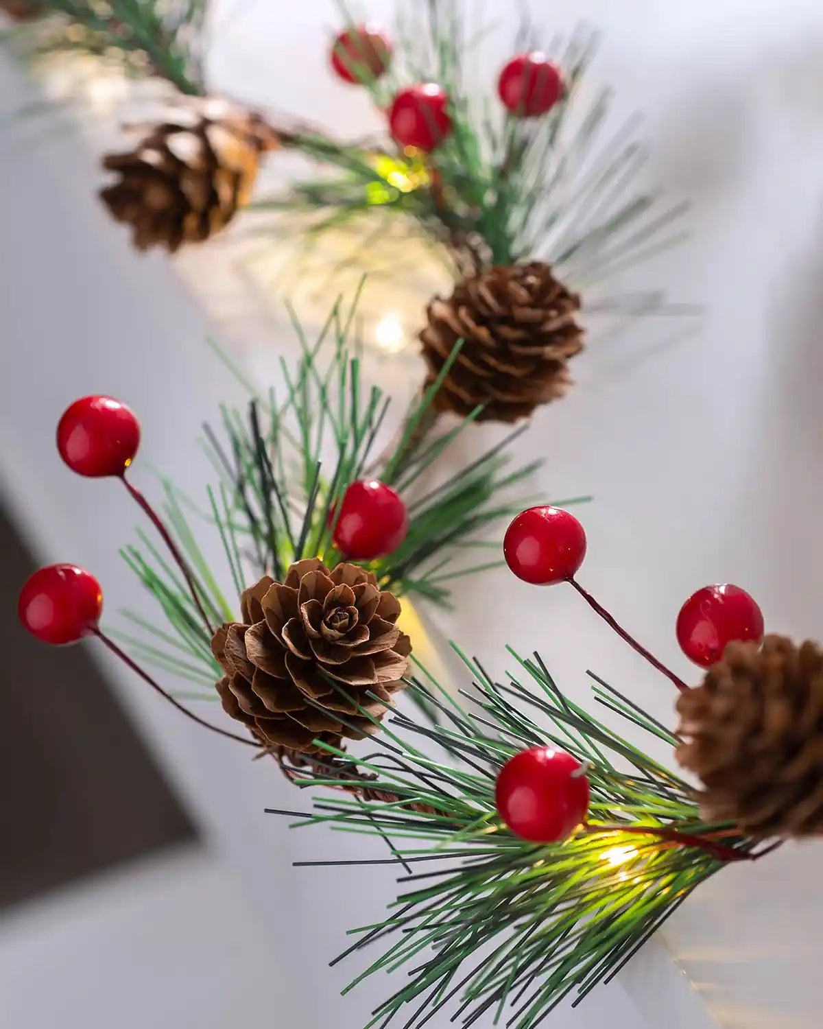 Close-up of red berries, pinecones and warm white LEDs on light string