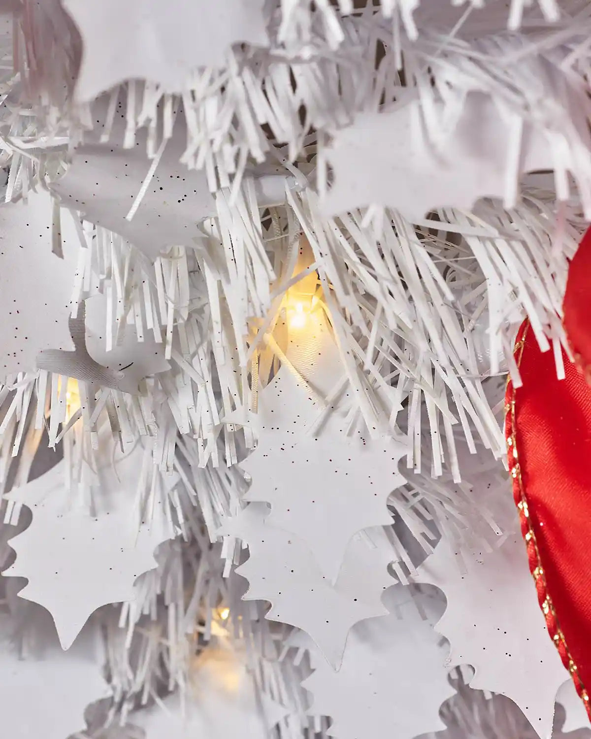 Close-up of warm white LED lights and white foliage on the red and white pop-up Christmas tree