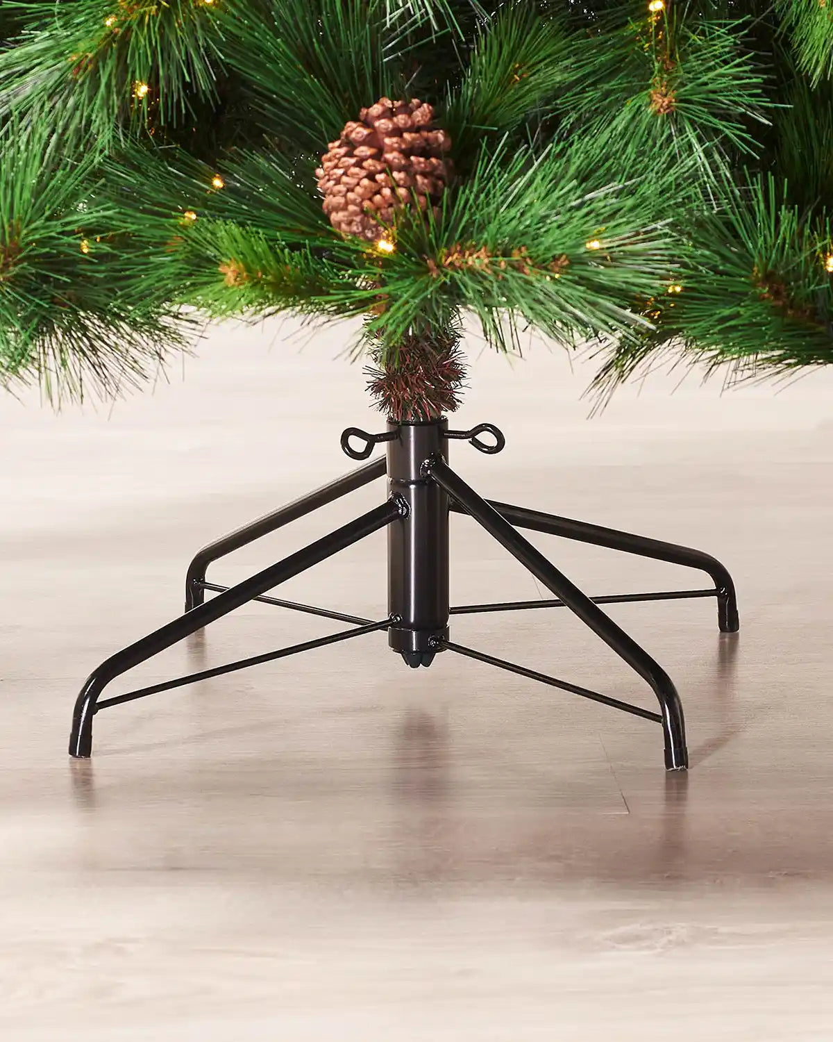Close-up of the metal stand and lower branches of a pre-lit Portland Spruce Christmas tree