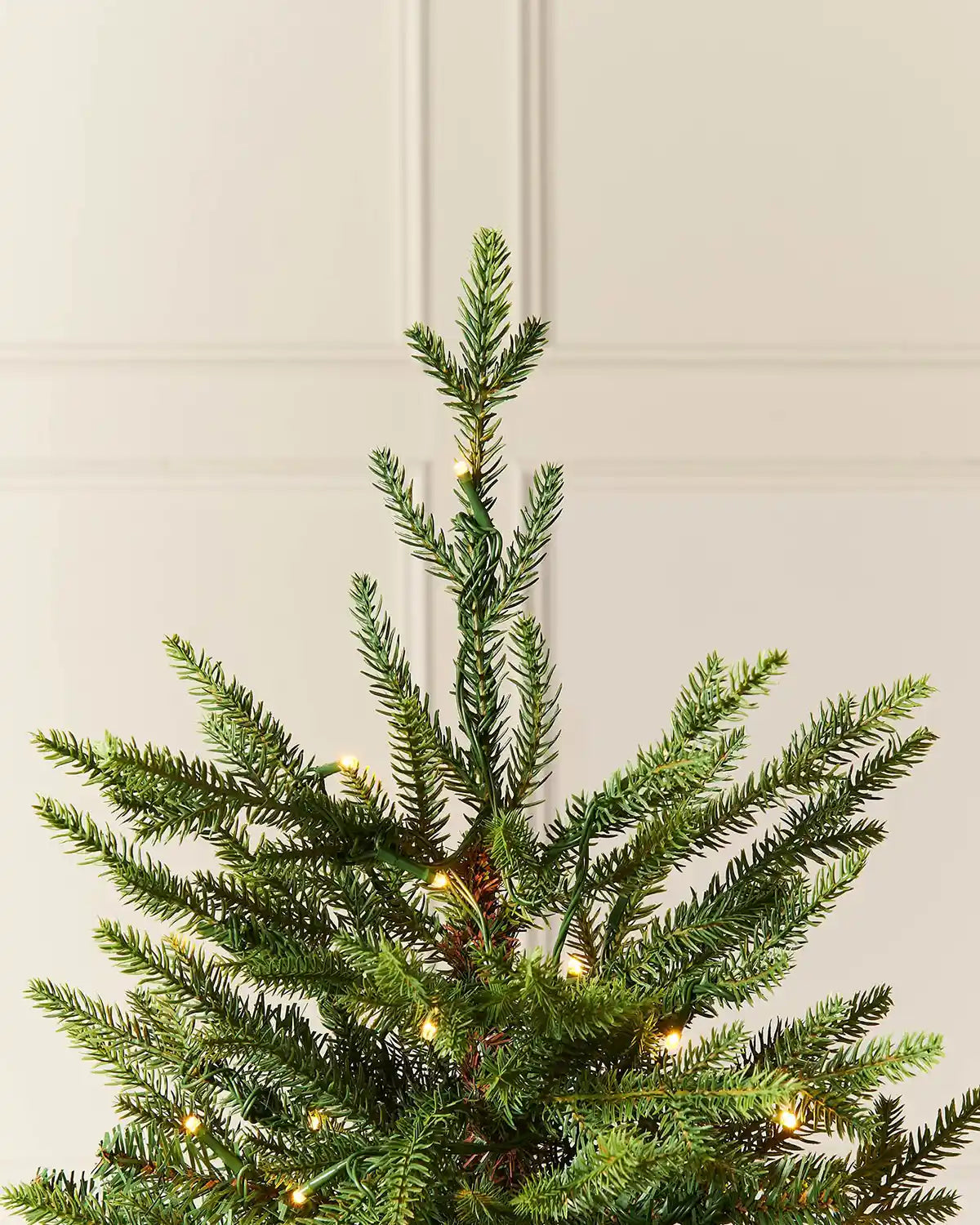 Close-up of the top branches and warm white lights on a 4 ft pre-lit potted pine Christmas tree