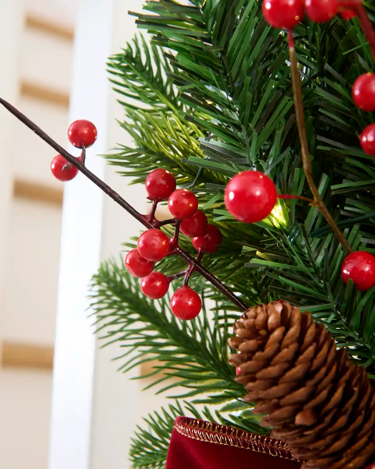 Close-up of red berry picks, green foliage and pinecone detail on the pre-lit garland swag.