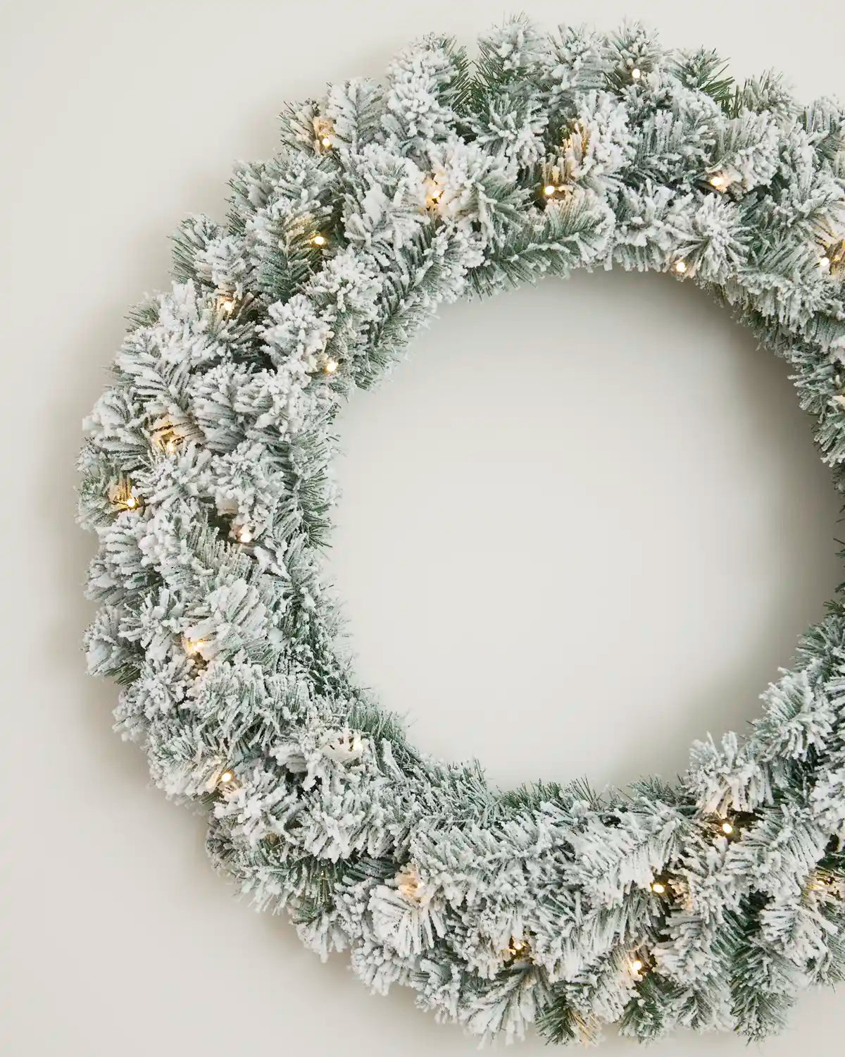 Close-up of a 76 cm snow flocked Christmas wreath with warm white LED lights.