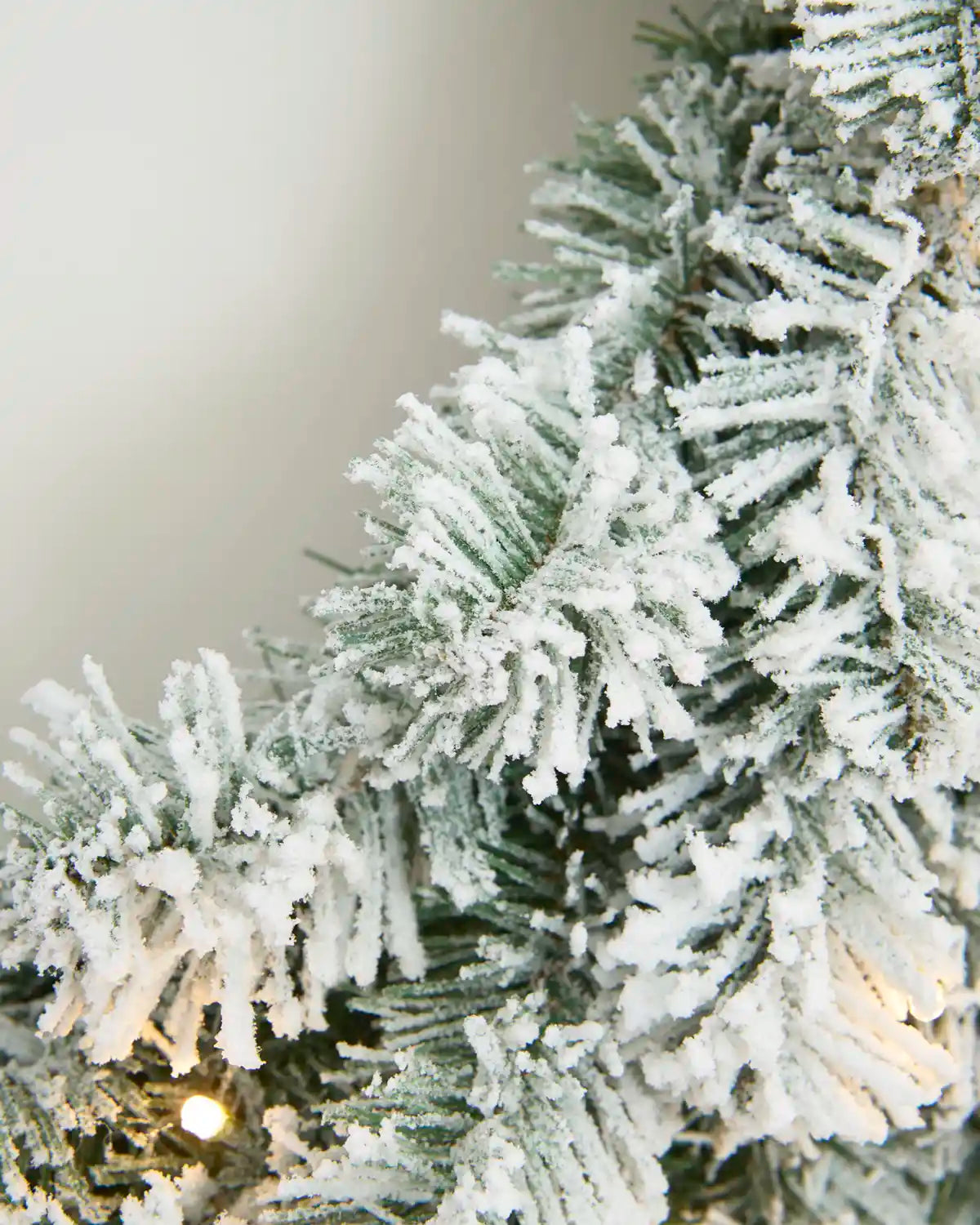Close-up of dense green Christmas wreath foliage with a textured snow flocked finish.