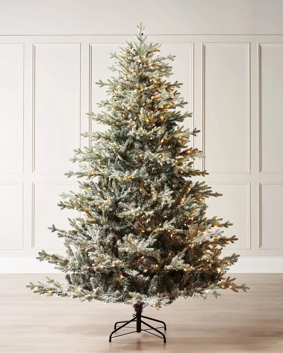 6 ft snow flocked artificial Fraser fir Christmas tree with warm lights displayed in a room