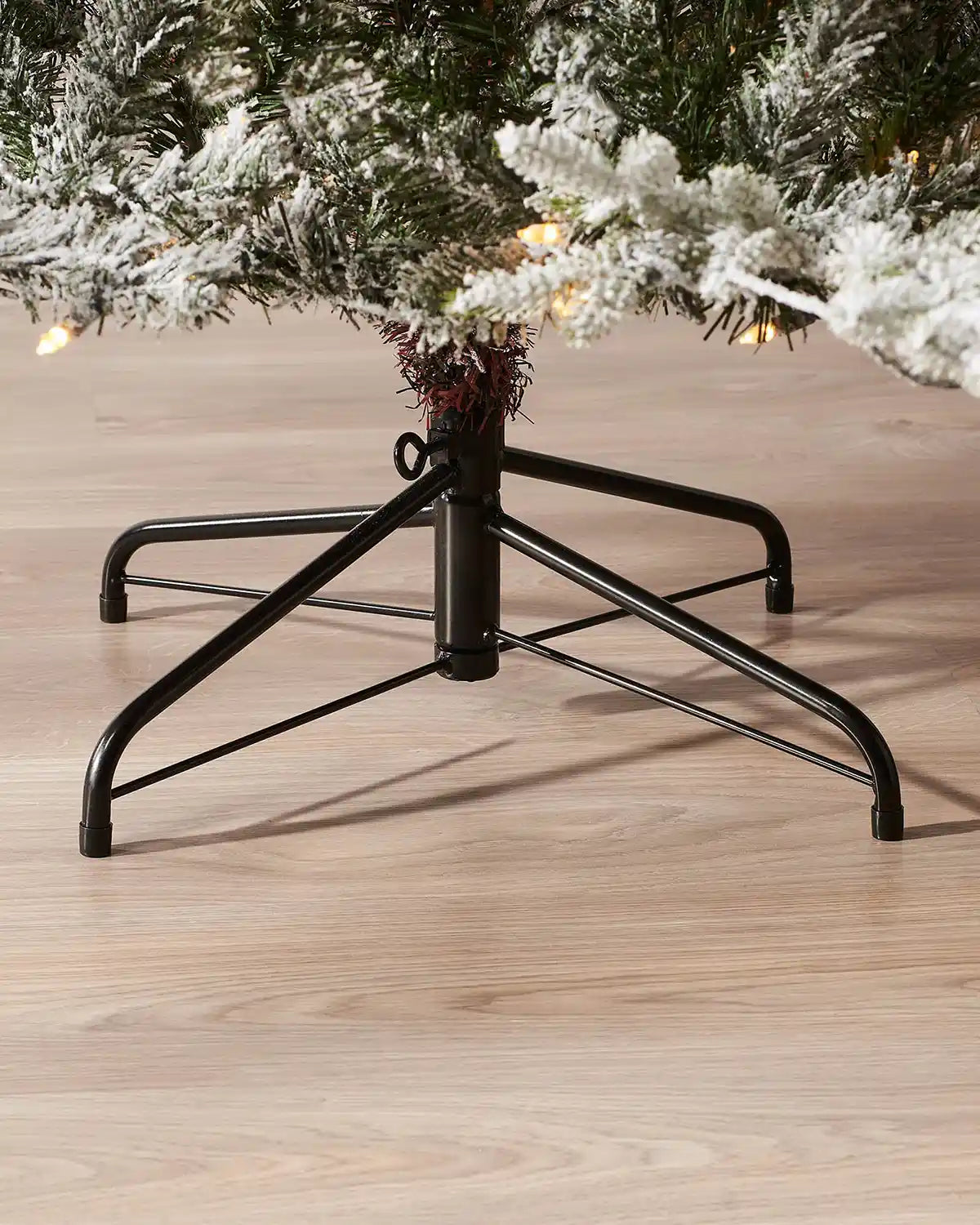 Foldable metal stand supporting a snow flocked artificial Christmas tree