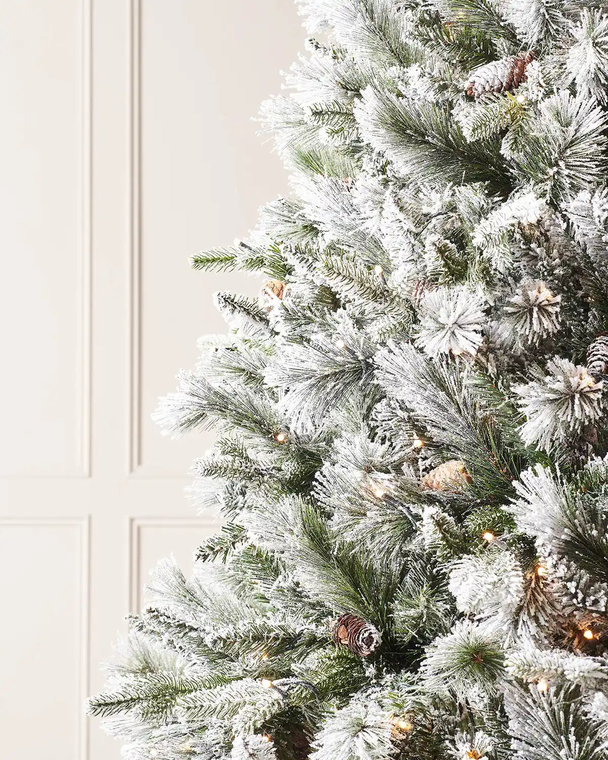 Close-up of frosted artificial Christmas tree branches with warm lights