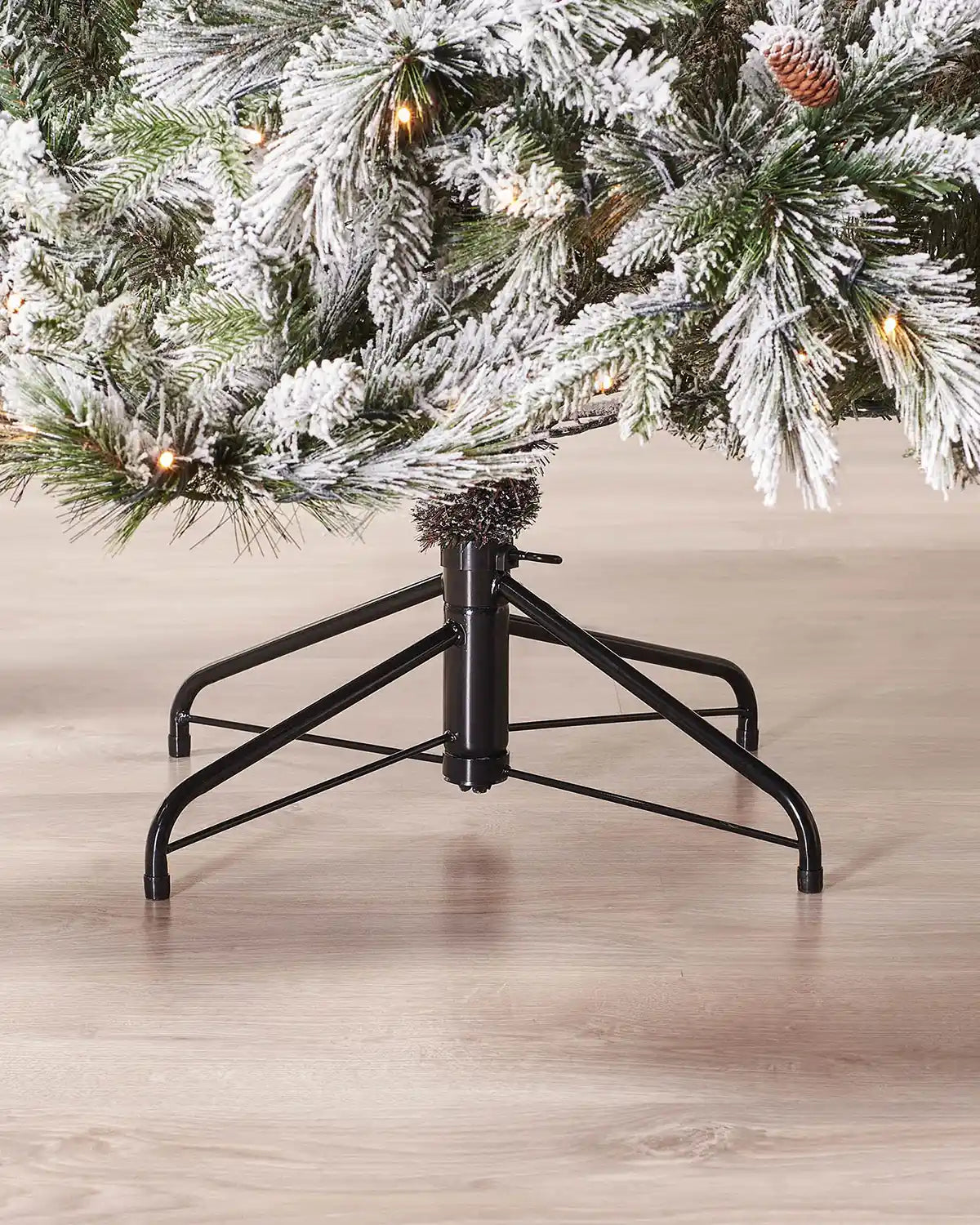Frosted artificial Christmas tree with black metal stand