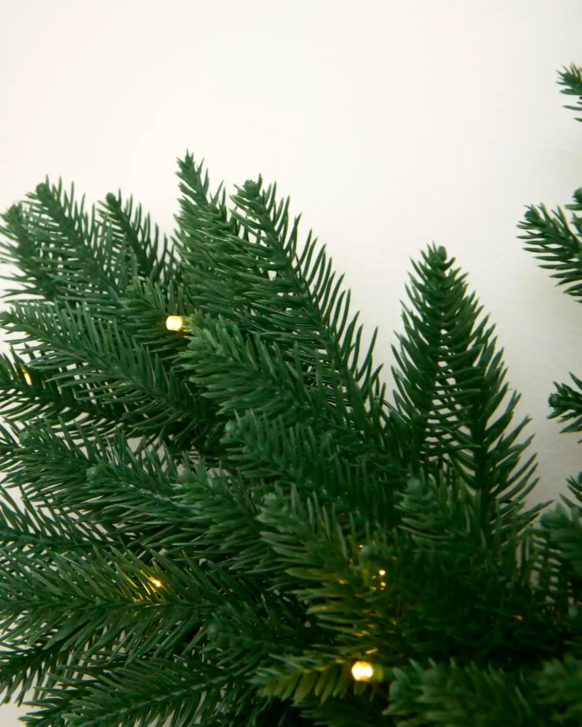 Close-up of the snowflake wreath showing textured green PE foliage and integrated warm white LEDs.