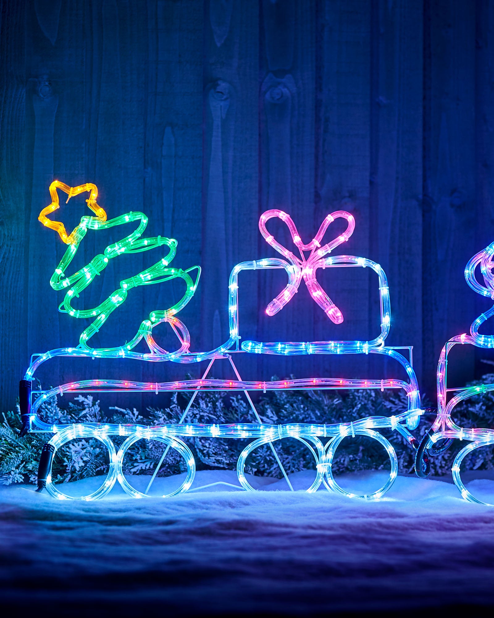 Close-up of the train carriage with a Christmas tree and present outlined in multi-coloured lights