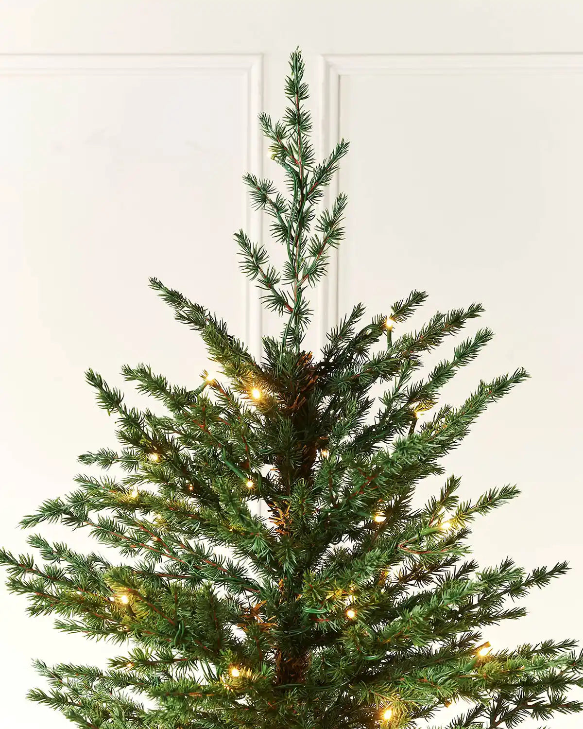 Top section of the pre-lit traditional fir Christmas tree with warm white LED lights
