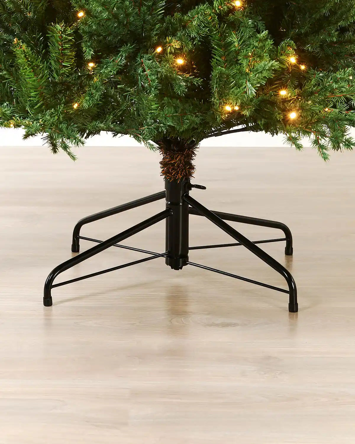 Black metal stand supporting the 7 ft pre-lit traditional fir Christmas tree