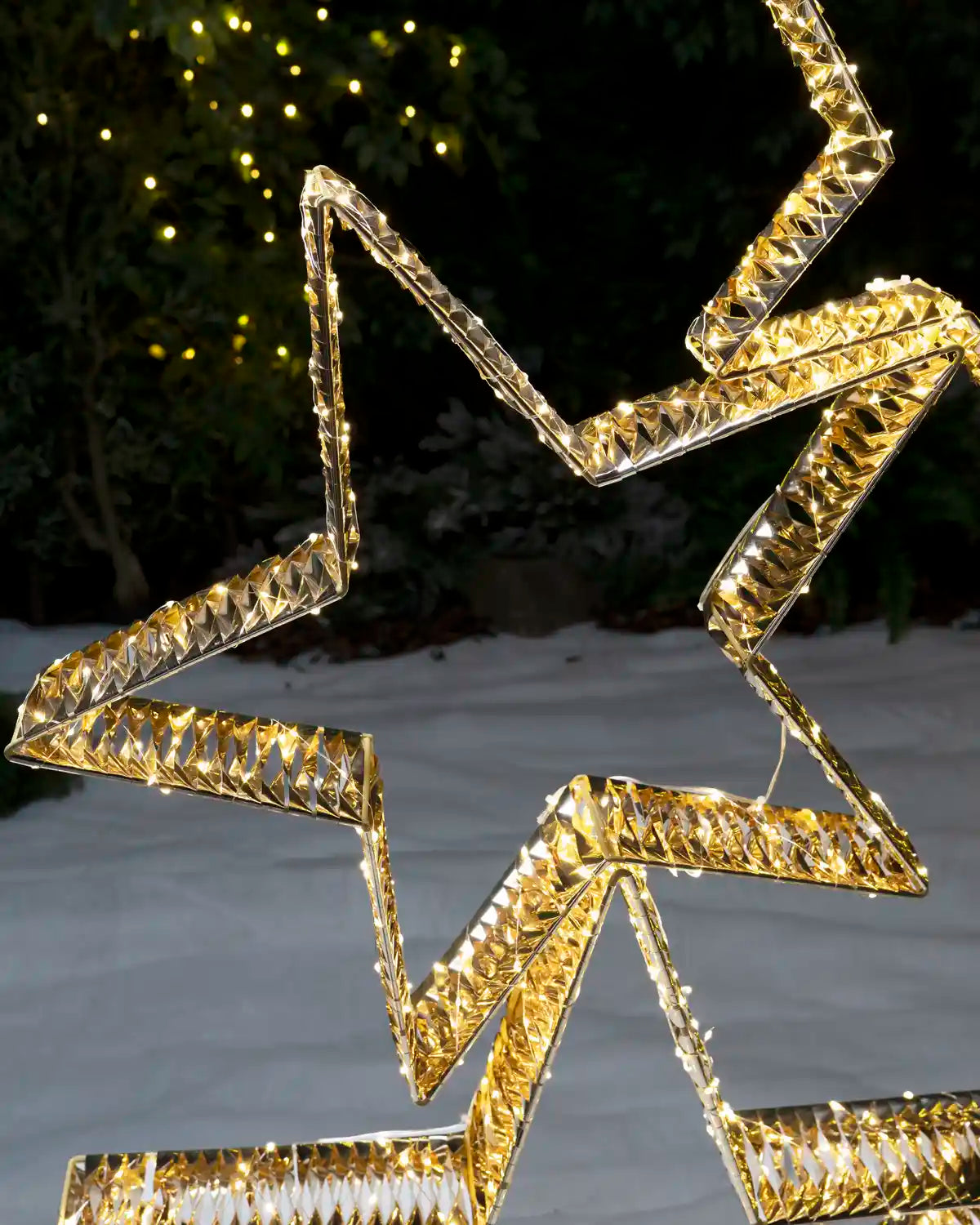 Close-up of the illuminated gold star stack showing layered star outlines and warm white LED lights.