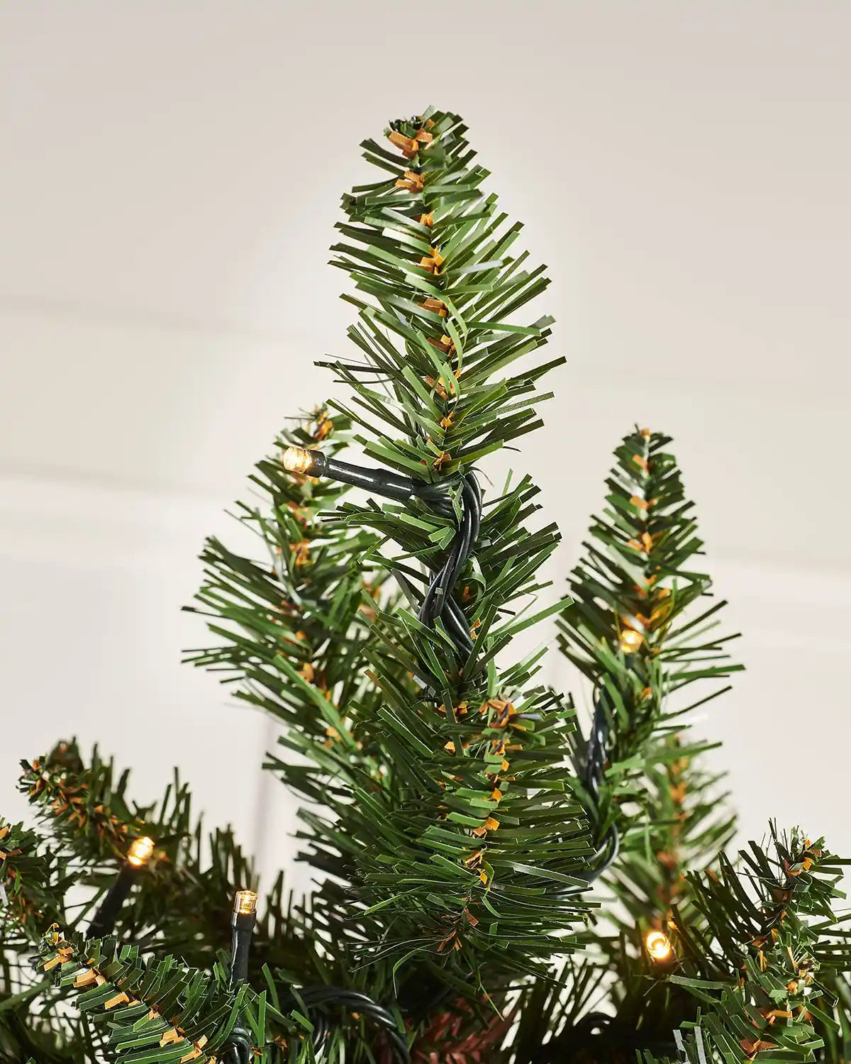 Close-up of the top branches and warm white lights on the 3 ft wall mounted Christmas tree