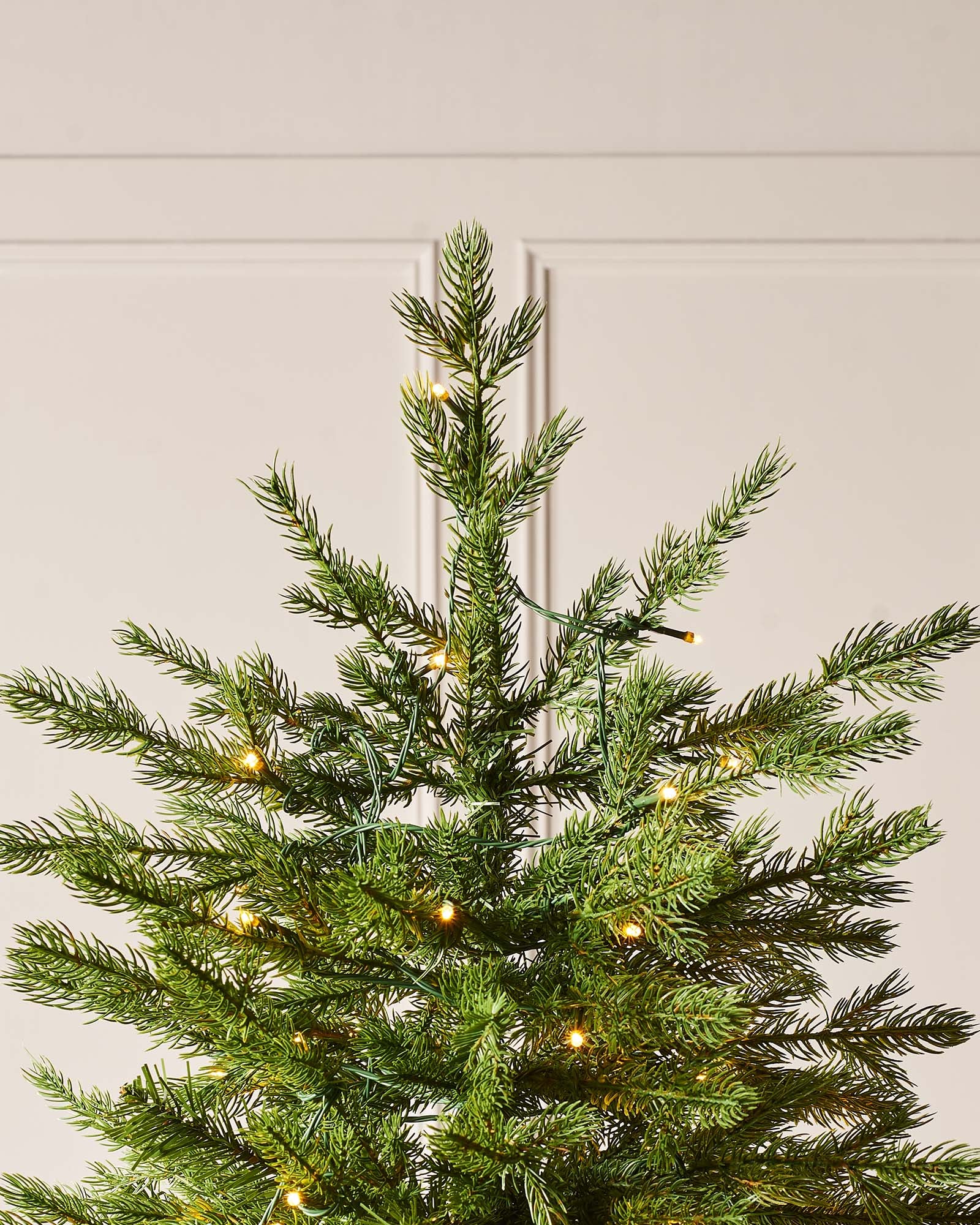 Top section of the Windsor fir Christmas tree with fine green branches and multicolour lights.