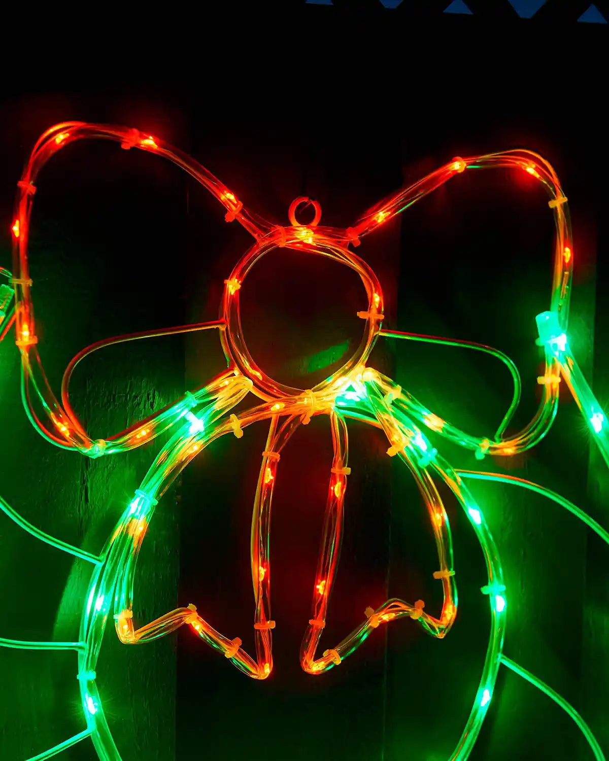 Close-up of the red bow and green wreath lights on the rope light display