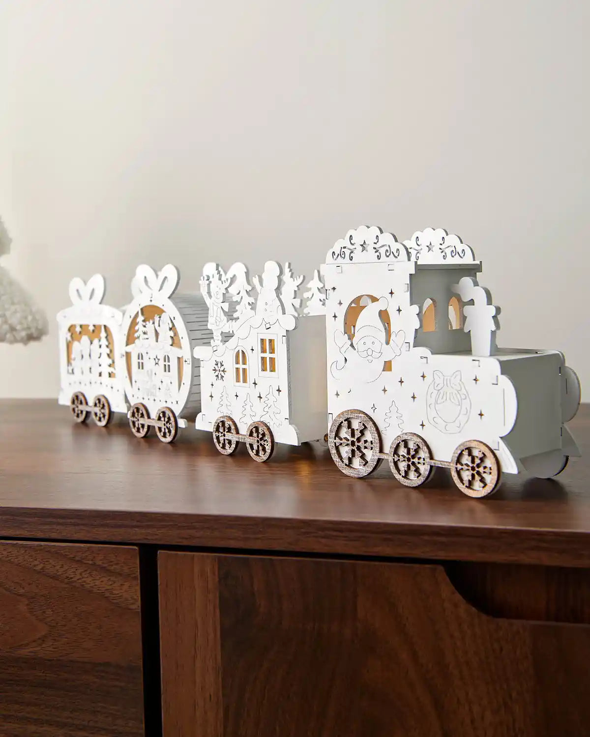 Full image of pre-lit white wooden train decoration on dark wood surface in front of white wall