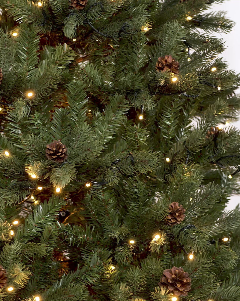 Pre-lit Craford Pine Christmas tree with dense PE/PVC branches, warm white LED lights, and realistic pinecones—lush, lifelike, and displayed against a neutral background for a cosy, traditional festive look.