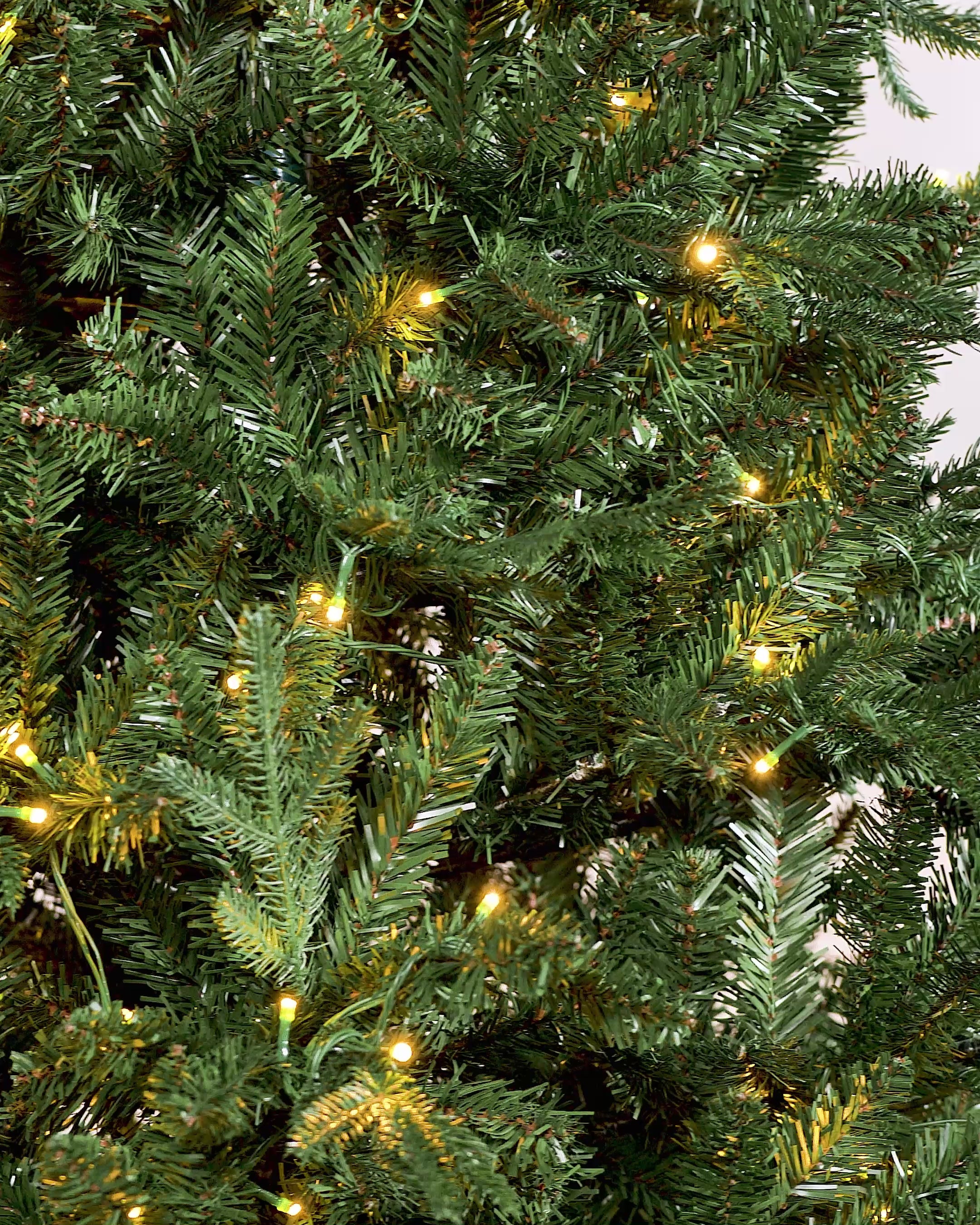 Load video: 5 ft pre-lit Grand Alaskan Fir Christmas tree with mixed PE and PVC branches, featuring dual warm white and multi-colour LED lights with multi-functional settings, displayed against a neutral background.