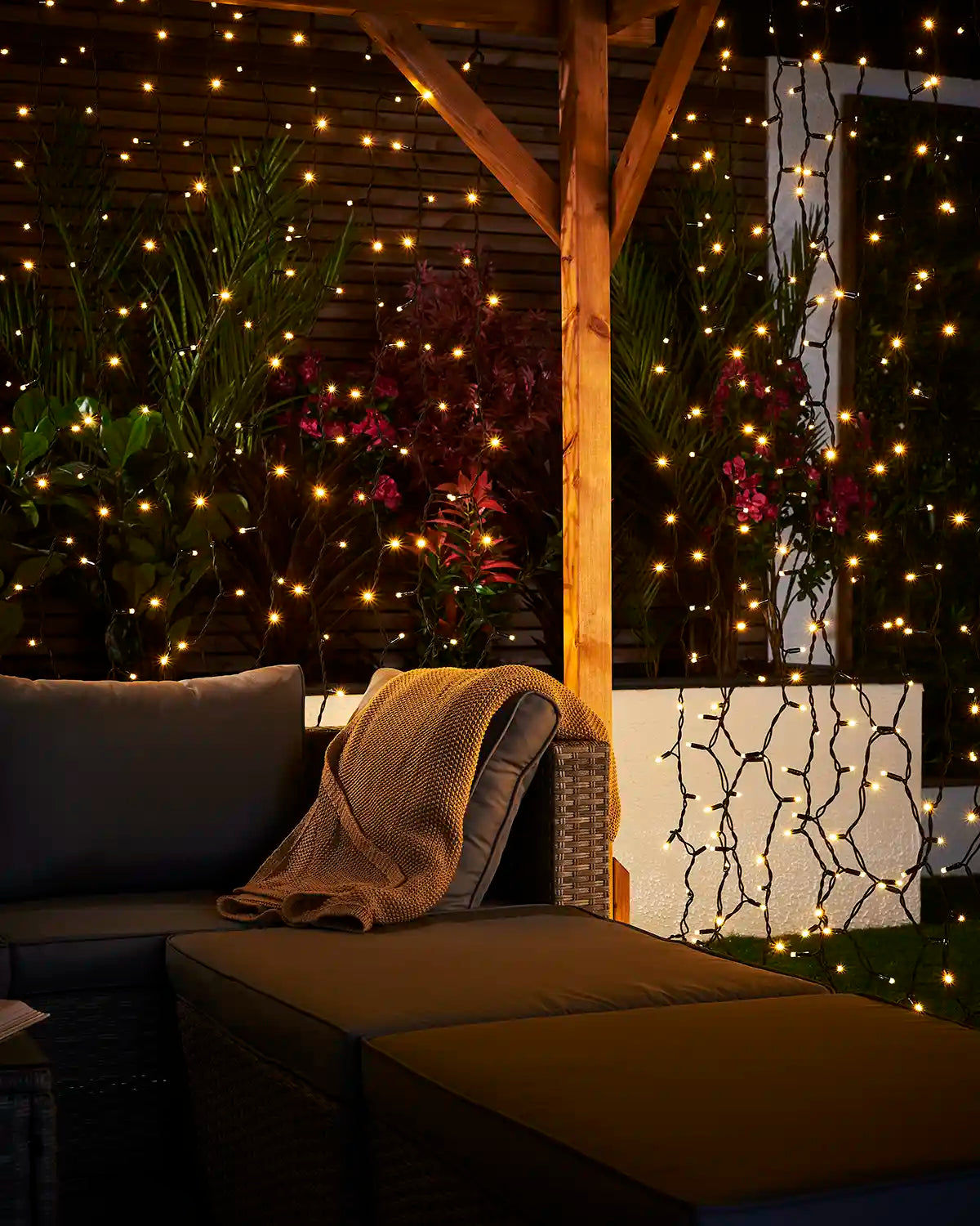 Warm white curtain lights on black cable displayed around a covered outdoor seating area.
