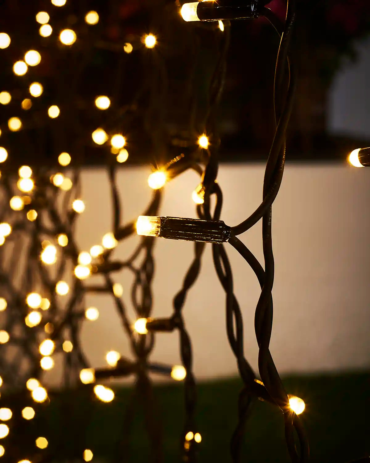 Close-up of warm white LEDs on black cable with curtain light strands softly glowing in the background.