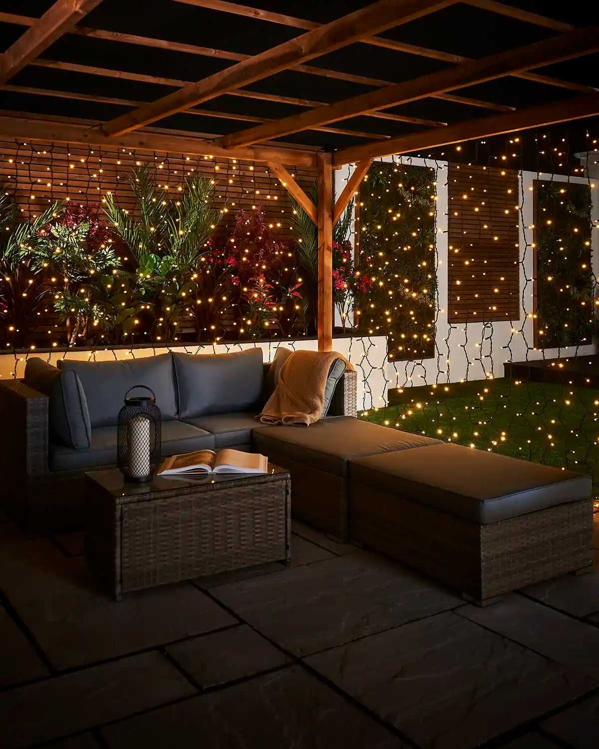 Warm white curtain lights on black cable decorating a patio seating area at night.