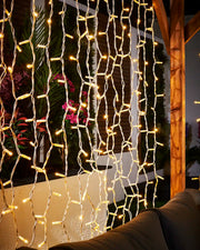 Warm white Pro Series curtain lights on white cable hanging in an outdoor seating area.