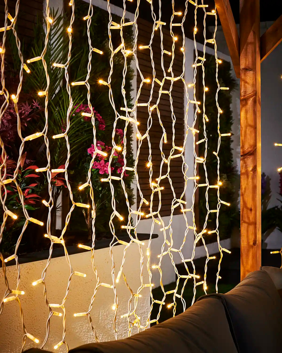 Warm white Pro Series curtain lights on white cable hanging in an outdoor seating area.