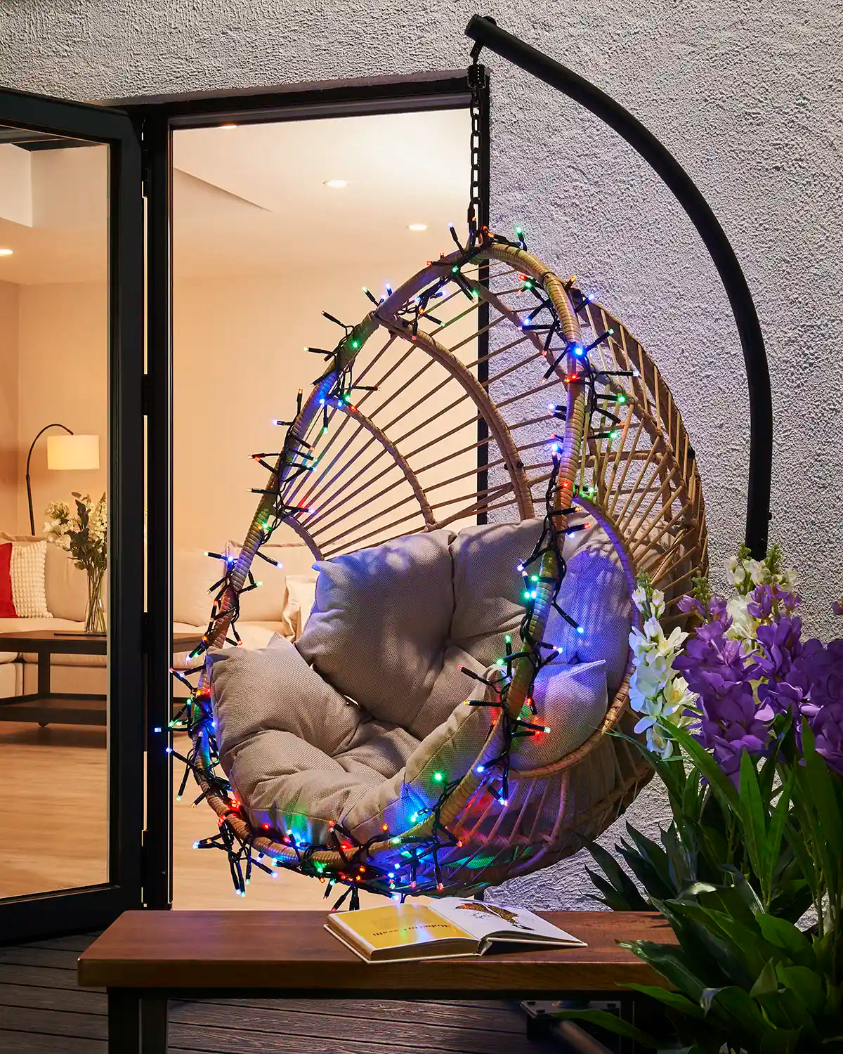 Multicolour cluster lights wrapped around an outdoor hanging chair.